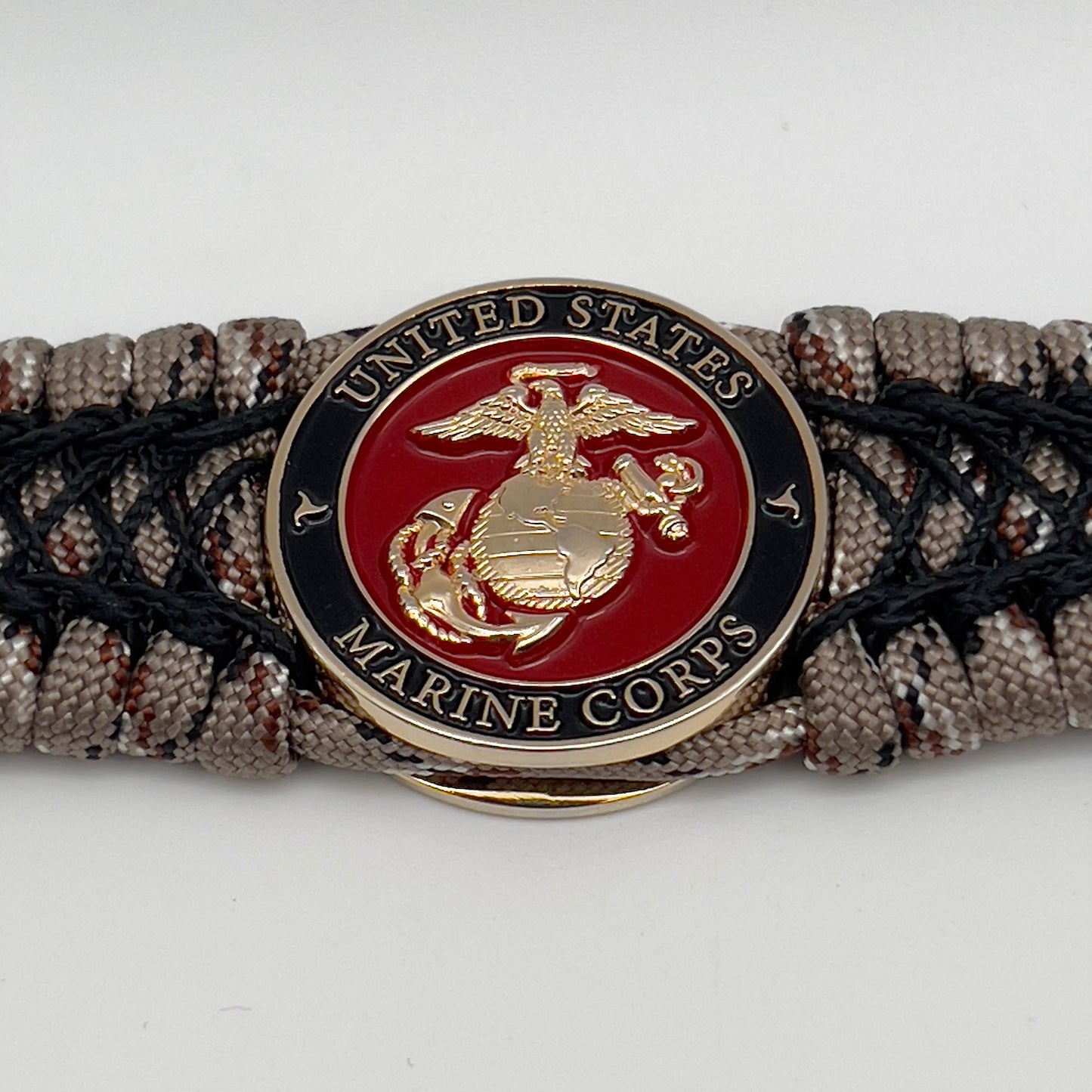 Thick, wide, rigid and comfortable braided United States Marine Corps bracelet featuring a 24K gold plated USMC Eagle Globe and Anchor medallion, a gold Cobra style tactical buckle and woven with Desert Camo 550 paracord and black nano and micro cord.