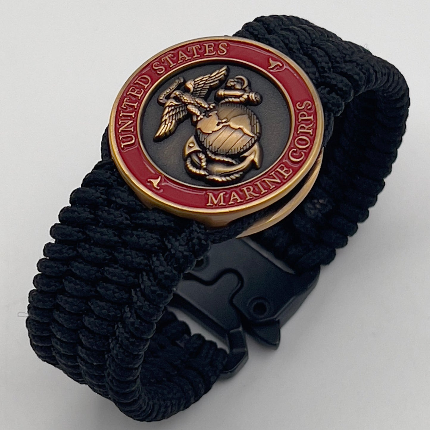 Thin, wide, very flexible and comfortable braided United States Marine Corps bracelet featuring a 24K antique gold plated USMC Eagle Globe and Anchor medallion engraved with the Punisher logo, a black Cobra style tactical buckle and woven with black Type-1 paracord.
