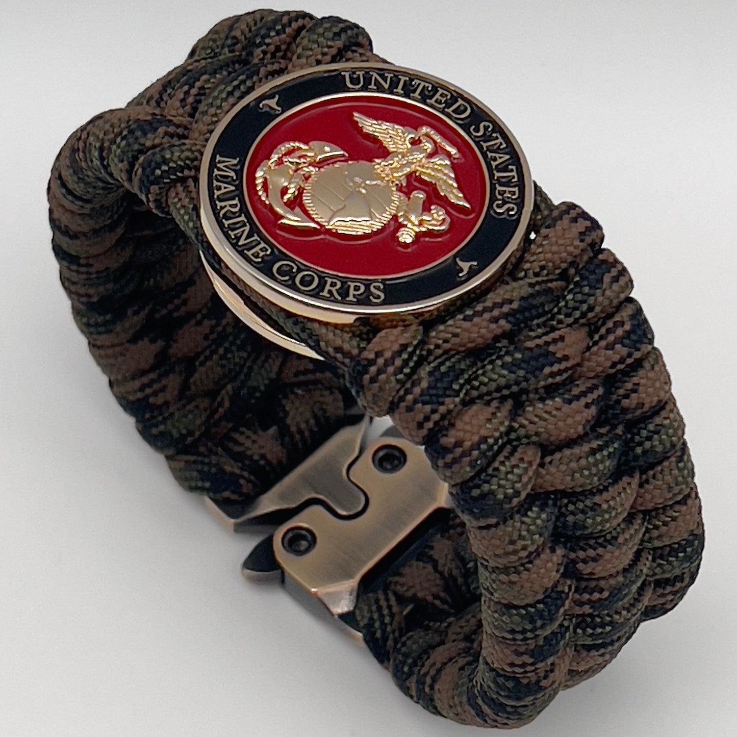 Thick, wide, semi-rigid and comfortable braided United States Marine Corps bracelet featuring a 24K gold plated USMC Eagle Globe and Anchor medallion, a gold Cobra style tactical buckle and woven with Woodland Camo 550 paracord.