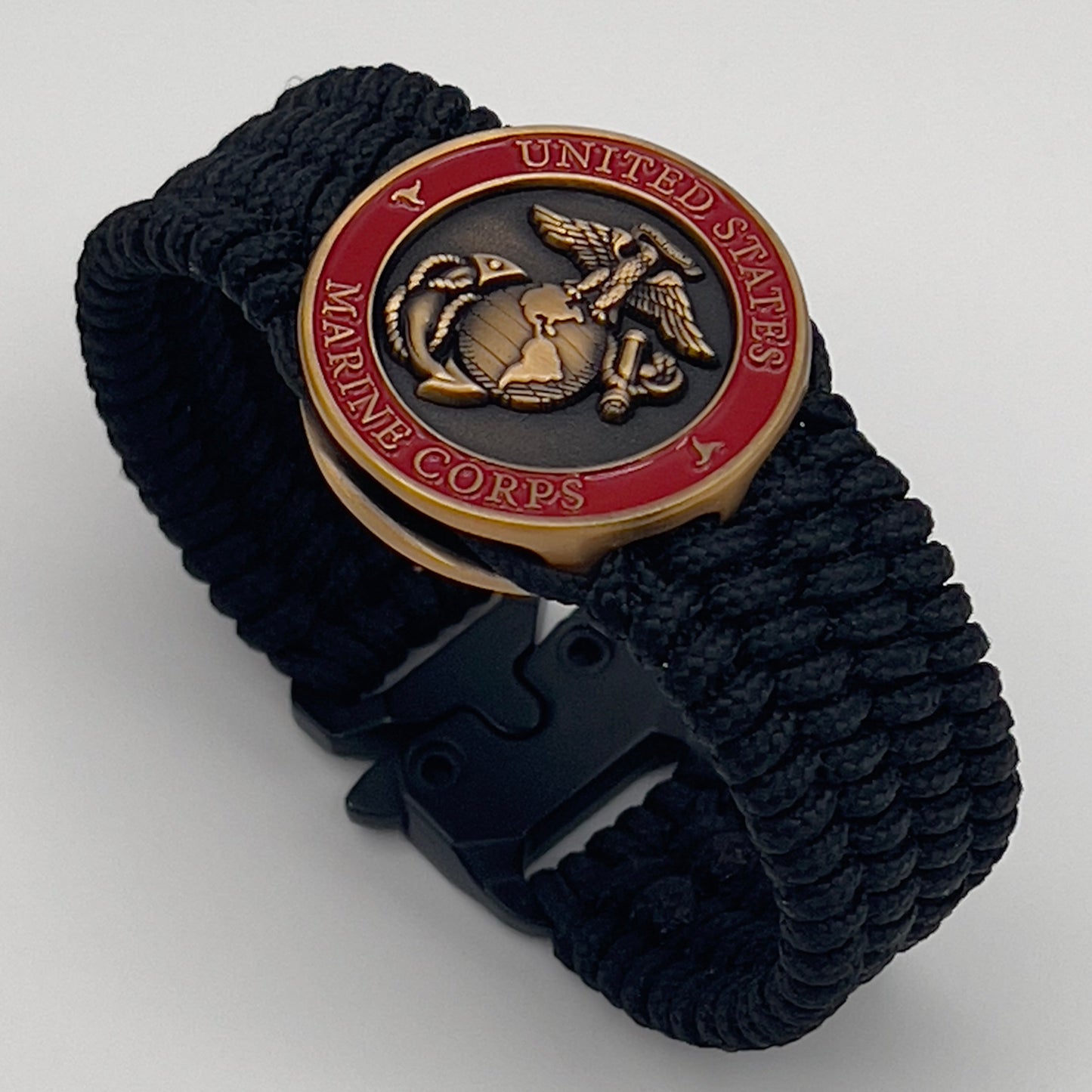 Thin, wide, very flexible and comfortable braided United States Marine Corps bracelet featuring a 24K antique gold plated USMC Eagle Globe and Anchor medallion engraved with the Punisher logo, a black Cobra style tactical buckle and woven with black Type-1 paracord.
