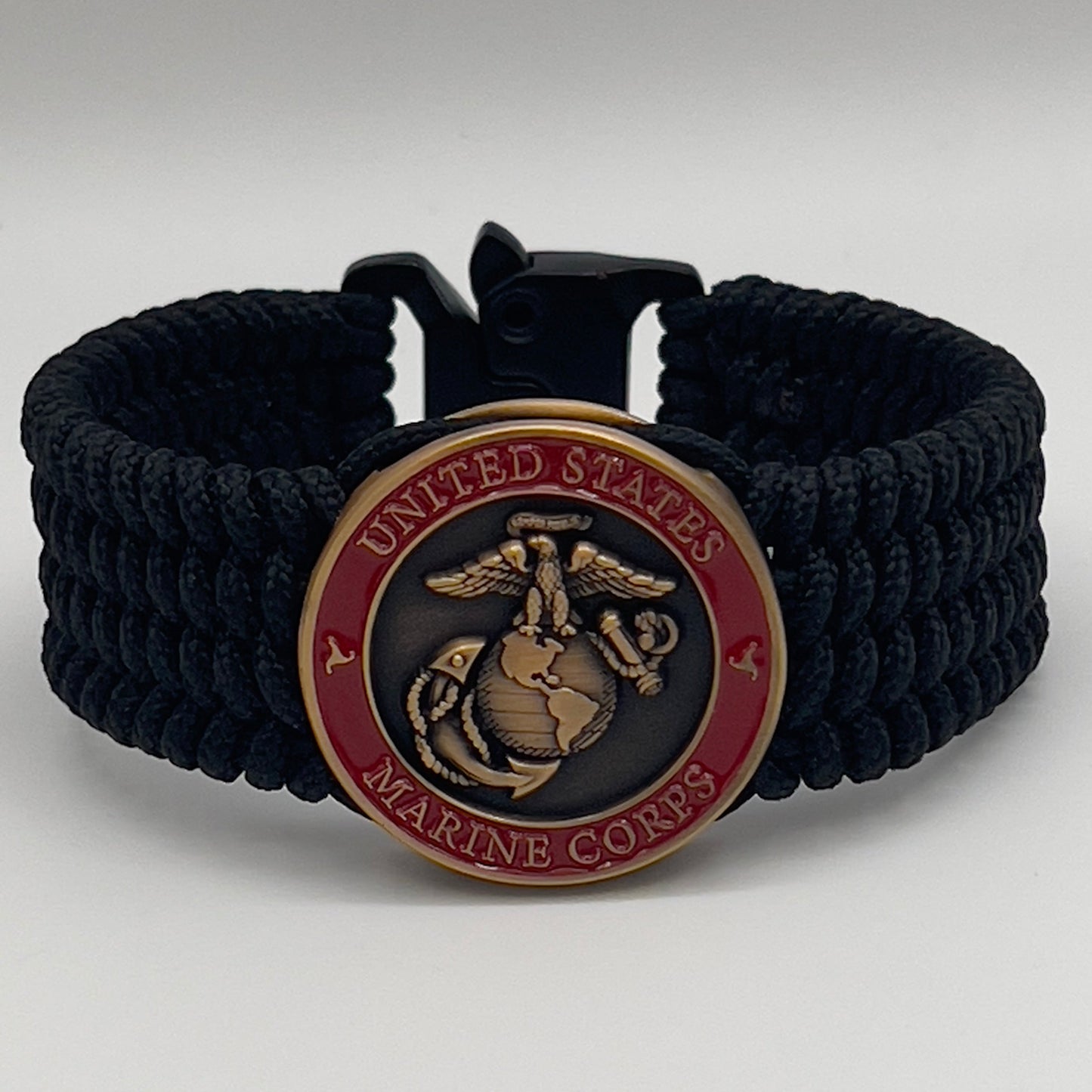 Thin, wide, very flexible and comfortable braided United States Marine Corps bracelet featuring a 24K antique gold plated USMC Eagle Globe and Anchor medallion engraved with the Punisher logo, a black Cobra style tactical buckle and woven with black Type-1 paracord.