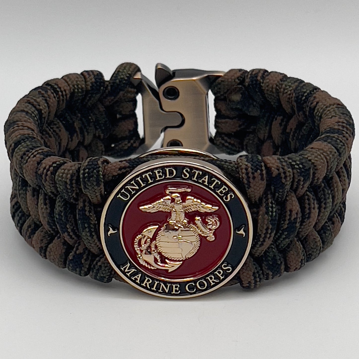 Thick, wide, semi-rigid and comfortable braided United States Marine Corps bracelet featuring a 24K gold plated USMC Eagle Globe and Anchor medallion, a gold Cobra style tactical buckle and woven with Woodland Camo 550 paracord.