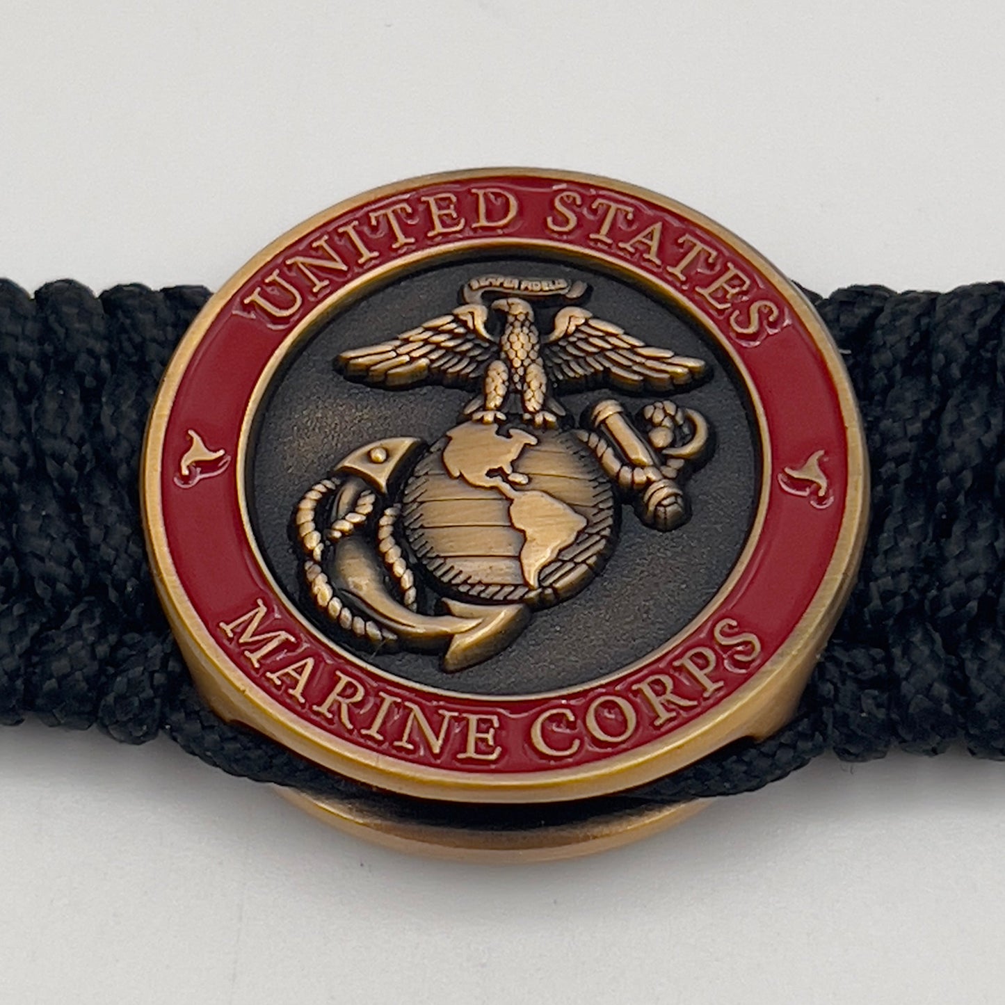 Thin, wide, very flexible and comfortable braided United States Marine Corps bracelet featuring a 24K antique gold plated USMC Eagle Globe and Anchor medallion engraved with the Punisher logo, a black Cobra style tactical buckle and woven with black Type-1 paracord.