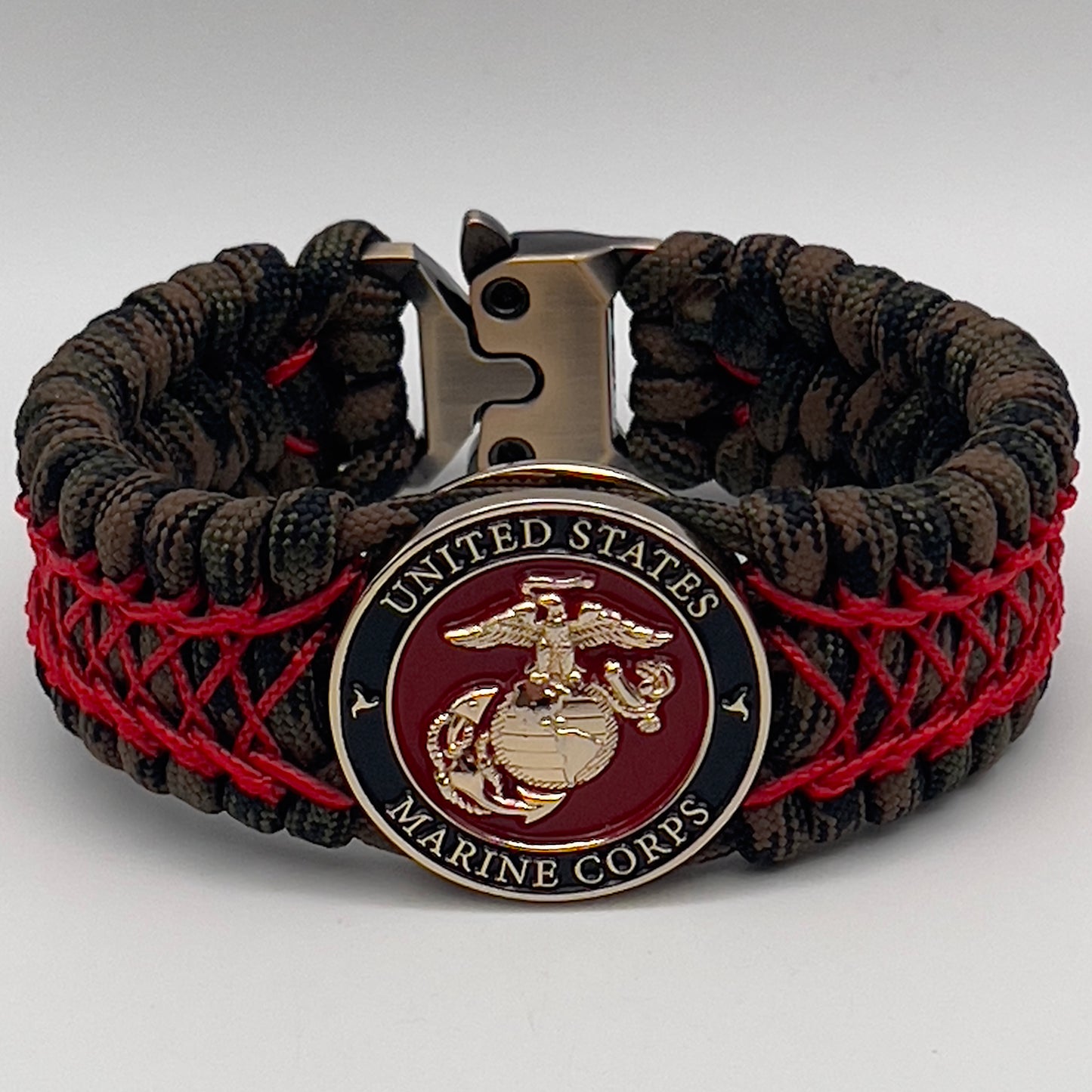 Thick, wide, rigid and comfortable braided United States Marine Corps bracelet featuring a 24K gold plated USMC Eagle Globe and Anchor medallion, a gold Cobra style tactical buckle and woven with Woodland Camo 550 paracord and Imperial Red nano and micro cord.