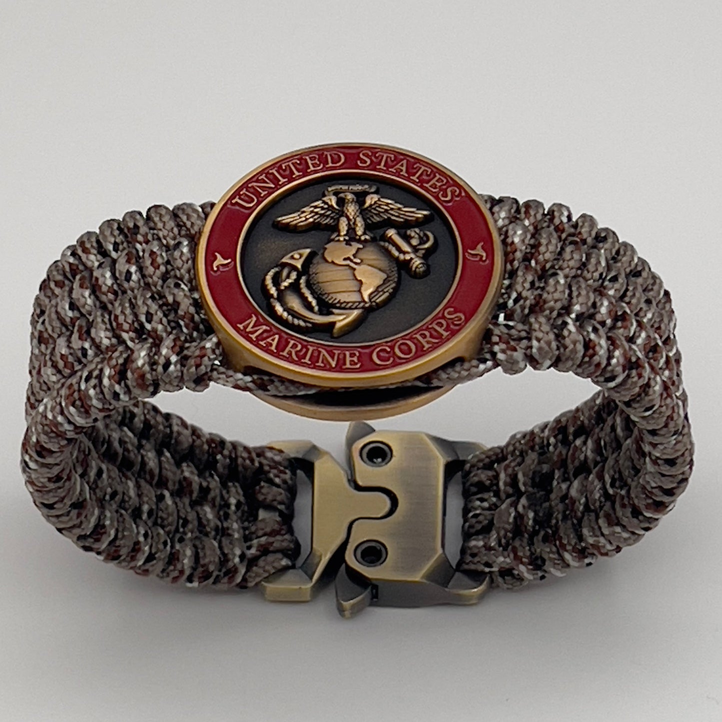 Thin, wide, very flexible and comfortable braided United States Marine Corps bracelet featuring a 24K antique gold plated USMC Eagle Globe and Anchor medallion engraved with the Punisher logo, a gold Cobra style tactical buckle and woven with Desert Camo Type-1 paracord.