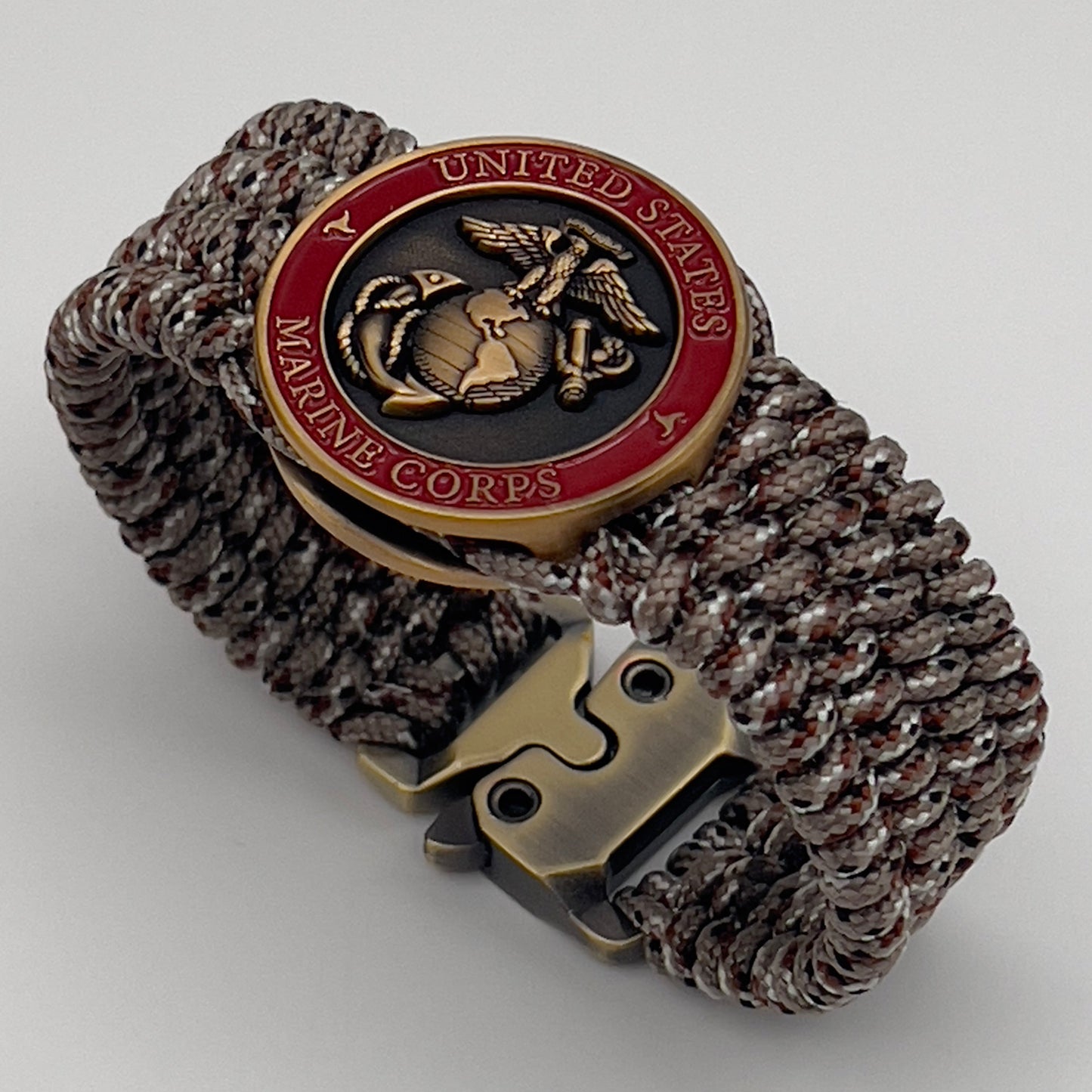 Thin, wide, very flexible and comfortable braided United States Marine Corps bracelet featuring a 24K antique gold plated USMC Eagle Globe and Anchor medallion engraved with the Punisher logo, a gold Cobra style tactical buckle and woven with Desert Camo Type-1 paracord.