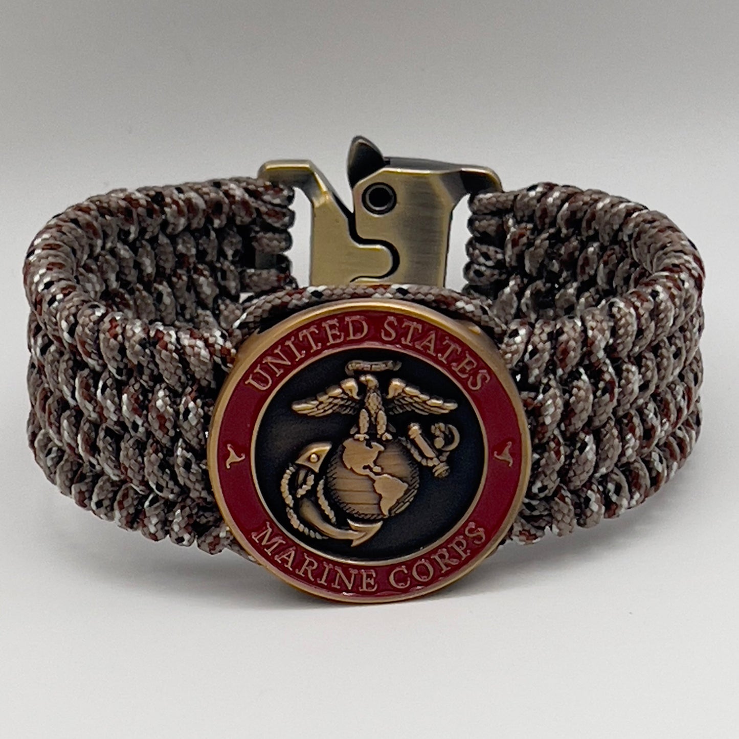 Thin, wide, very flexible and comfortable braided United States Marine Corps bracelet featuring a 24K antique gold plated USMC Eagle Globe and Anchor medallion engraved with the Punisher logo, a gold Cobra style tactical buckle and woven with Desert Camo Type-1 paracord.