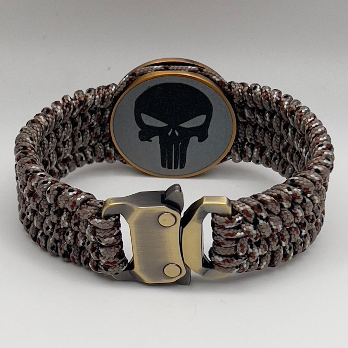 Thin, wide, very flexible and comfortable braided United States Marine Corps bracelet featuring a 24K antique gold plated USMC Eagle Globe and Anchor medallion engraved with the Punisher logo, a gold Cobra style tactical buckle and woven with Desert Camo Type-1 paracord.