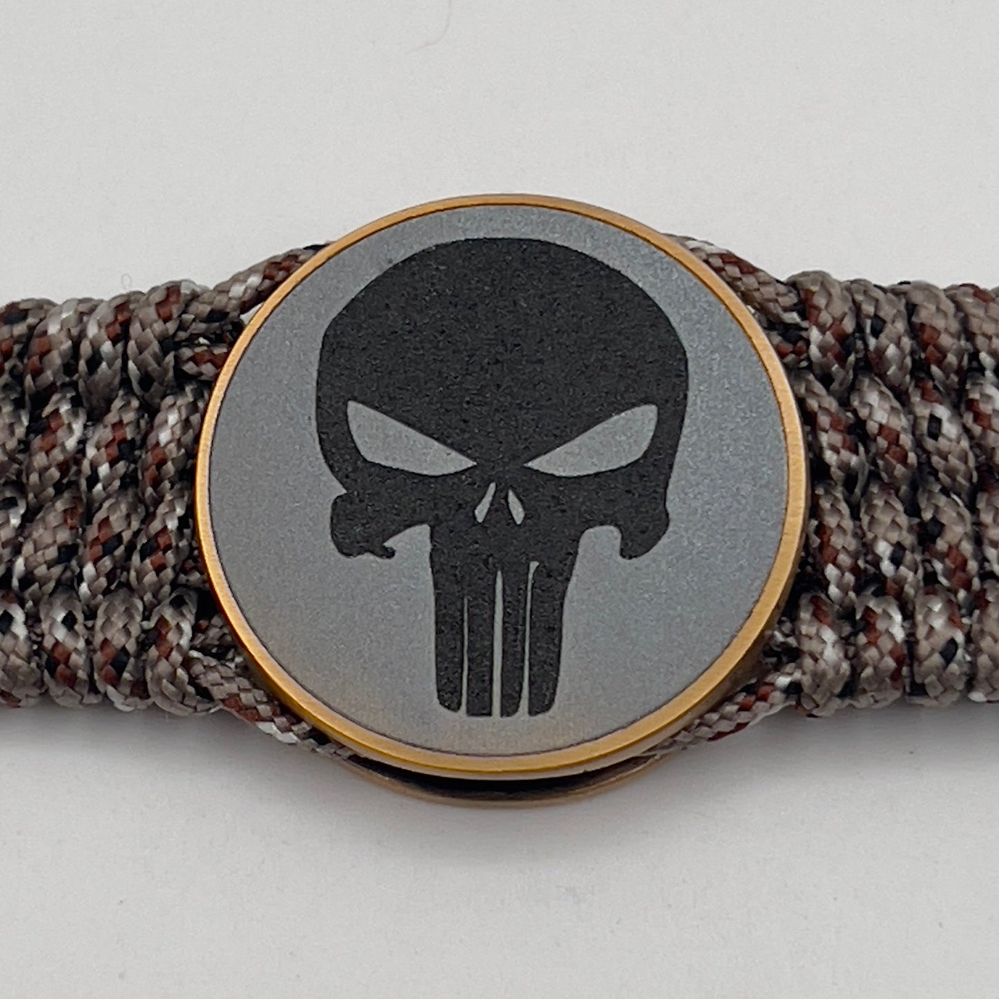 Thin, wide, very flexible and comfortable braided United States Marine Corps bracelet featuring a 24K antique gold plated USMC Eagle Globe and Anchor medallion engraved with the Punisher logo, a gold Cobra style tactical buckle and woven with Desert Camo Type-1 paracord.