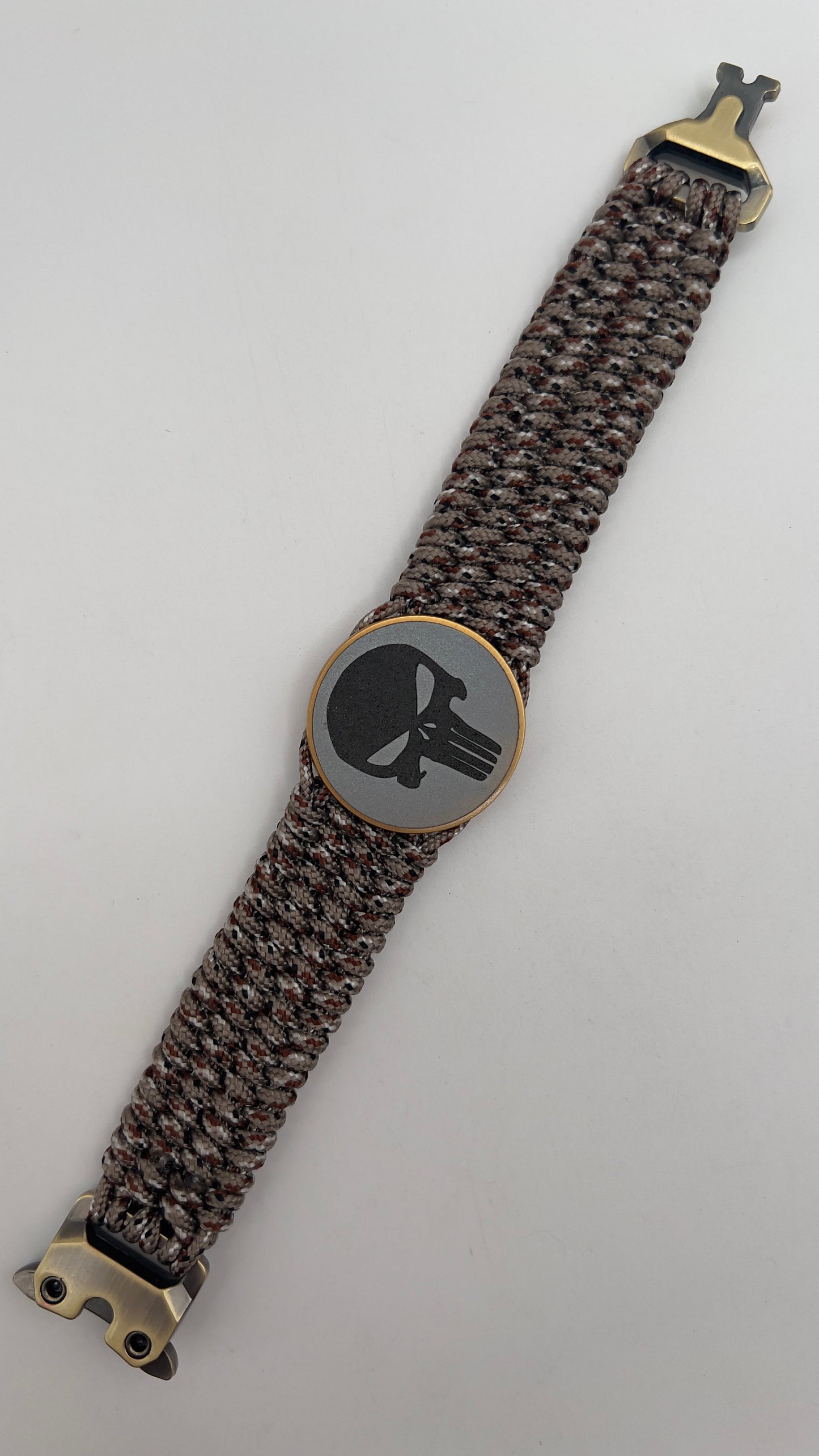 Thin, wide, very flexible and comfortable braided United States Marine Corps bracelet featuring a 24K antique gold plated USMC Eagle Globe and Anchor medallion engraved with the Punisher logo, a gold Cobra style tactical buckle and woven with Desert Camo Type-1 paracord.