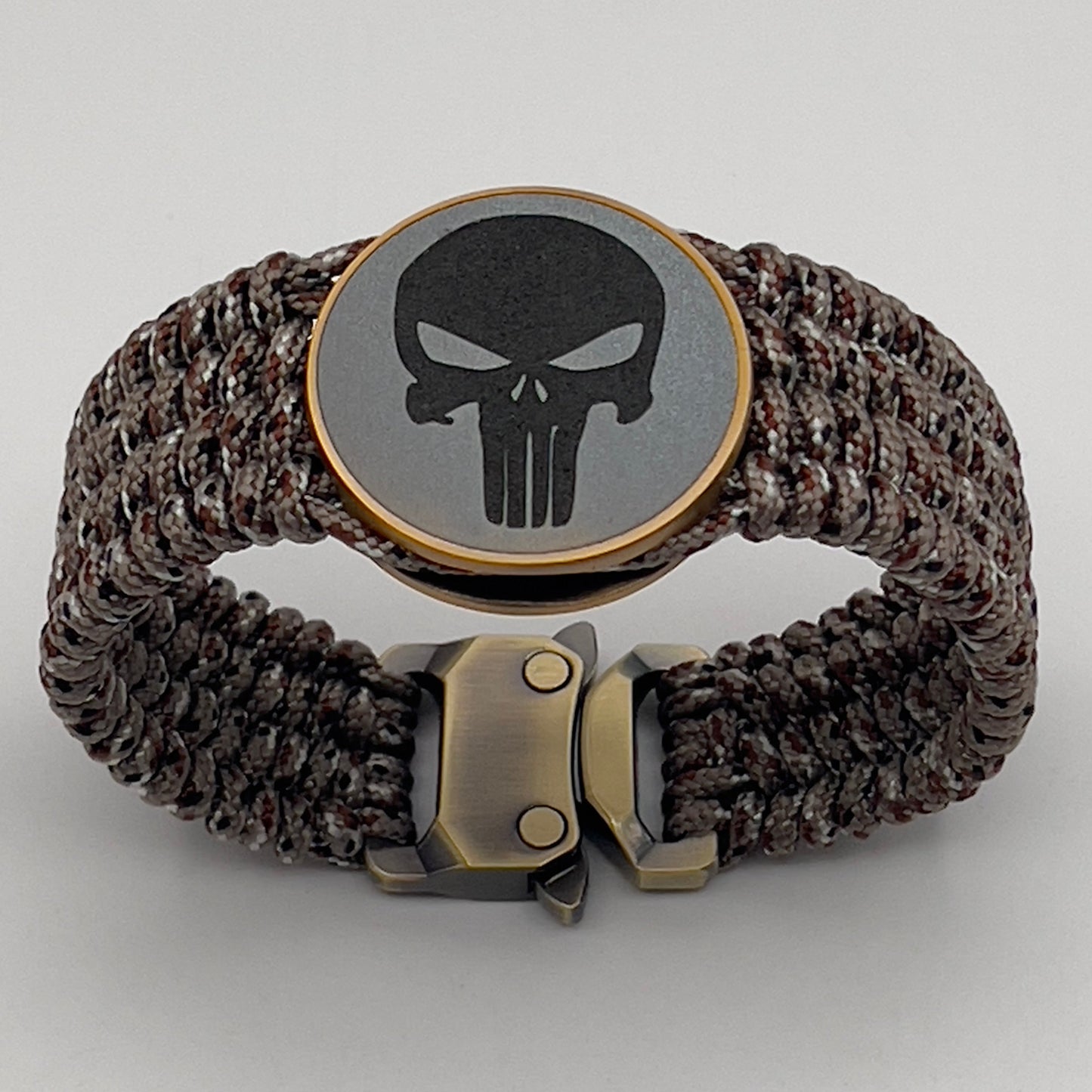 Thin, wide, very flexible and comfortable braided United States Marine Corps bracelet featuring a 24K antique gold plated USMC Eagle Globe and Anchor medallion engraved with the Punisher logo, a gold Cobra style tactical buckle and woven with Desert Camo Type-1 paracord.