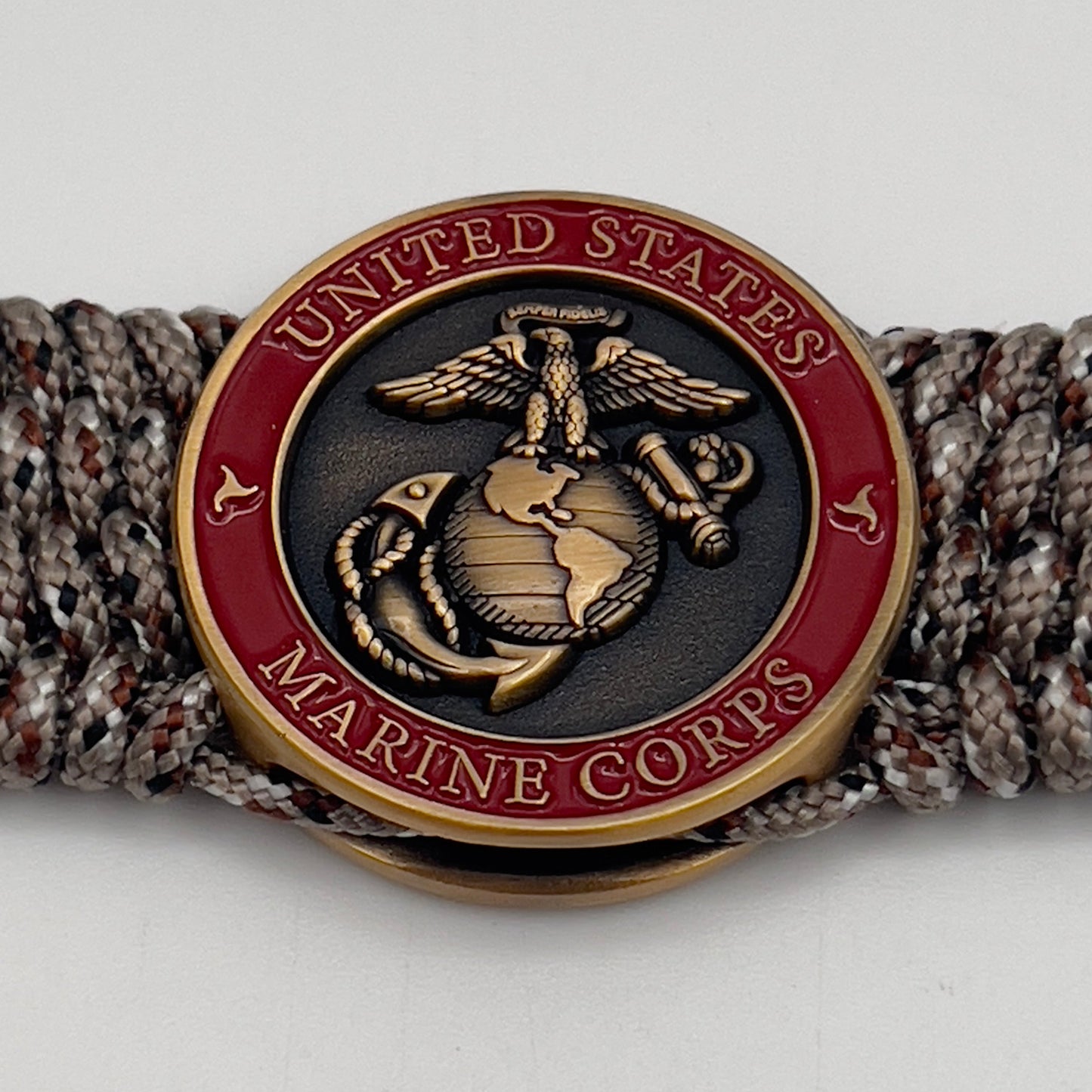 Thin, wide, very flexible and comfortable braided United States Marine Corps bracelet featuring a 24K antique gold plated USMC Eagle Globe and Anchor medallion engraved with the Punisher logo, a gold Cobra style tactical buckle and woven with Desert Camo Type-1 paracord.