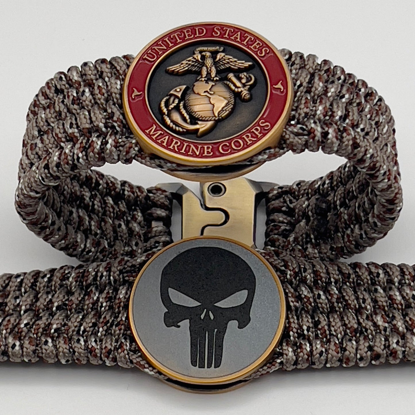 Thin, wide, very flexible and comfortable braided United States Marine Corps bracelet featuring a 24K antique gold plated USMC Eagle Globe and Anchor medallion engraved with the Punisher logo, a gold Cobra style tactical buckle and woven with Desert Camo Type-1 paracord.