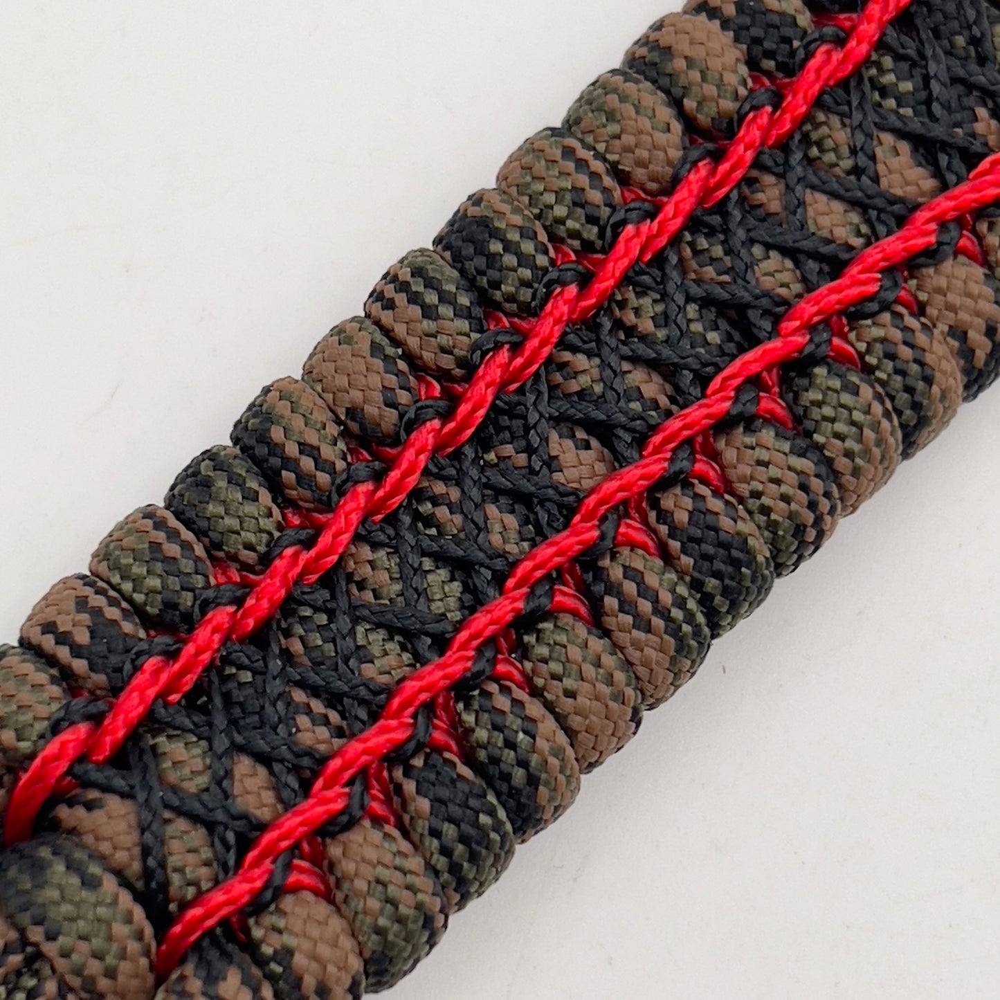 Thick, wide, rigid and comfortable braided United States Marine Corps bracelet featuring a 24K gold plated USMC Eagle Globe and Anchor medallion, a gold Cobra style tactical buckle and woven with Woodland Camo 550 paracord and Imperial Red micro and black nano cord.