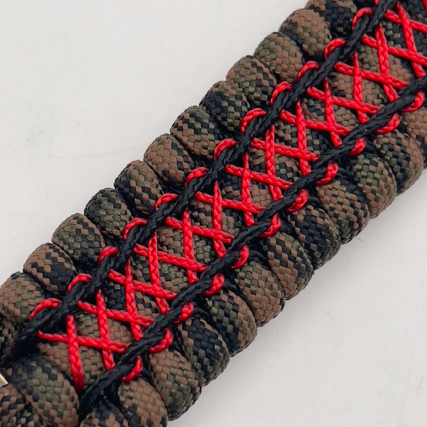 Thick, wide, rigid and comfortable braided United States Marine Corps bracelet featuring a 24K gold plated USMC Eagle Globe and Anchor medallion, a gold Cobra style tactical buckle and woven with Woodland Camo 550 paracord and Imperial Red micro and black nano cord.