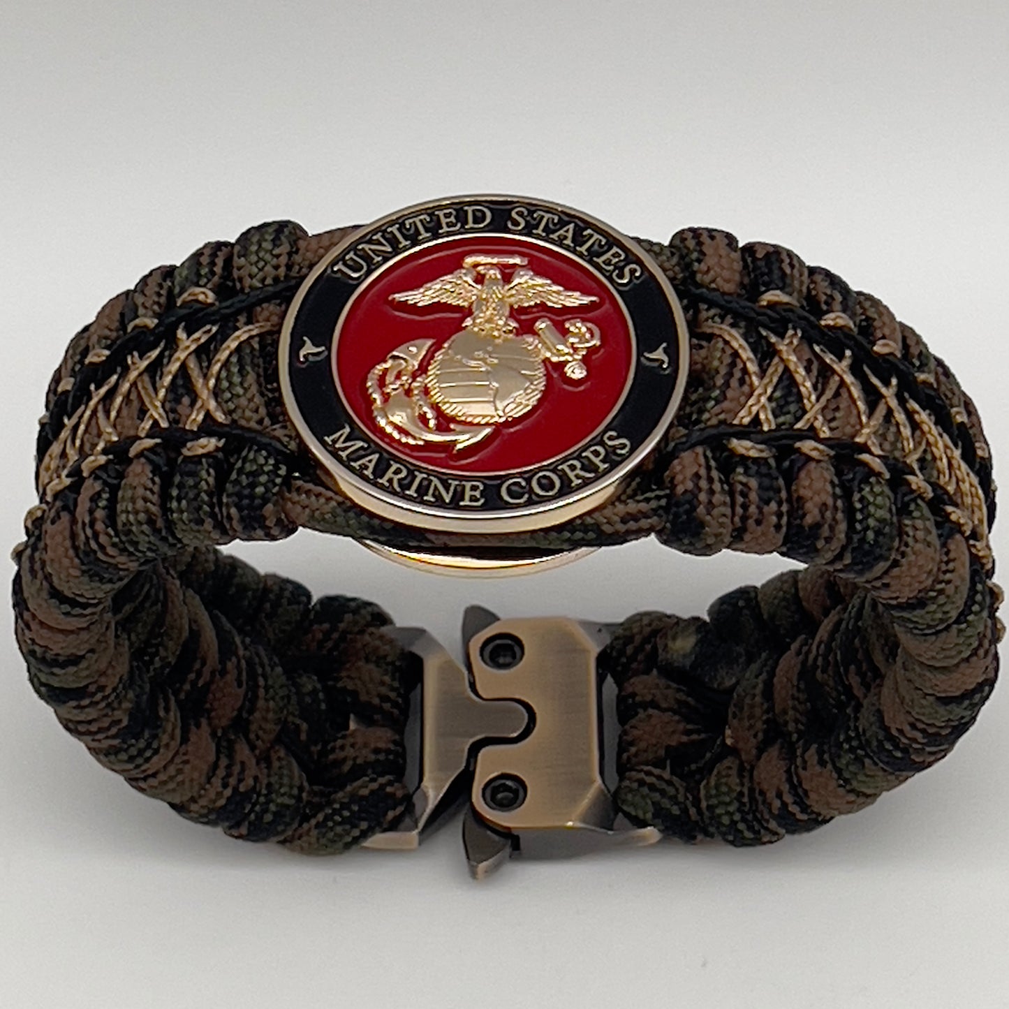 Thick, wide, rigid and comfortable braided United States Marine Corps bracelet featuring a 24K gold plated USMC Eagle Globe and Anchor medallion, a gold Cobra style tactical buckle and woven with Woodland 550 paracord, black micro and tan nano cord.