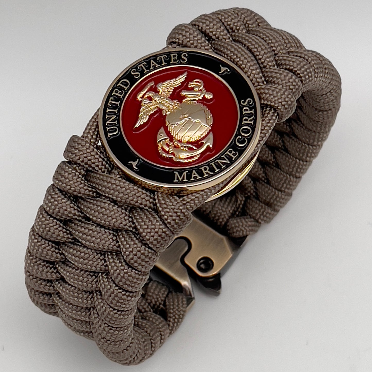 Thick, wide, semi-rigid and comfortable braided United States Marine Corps bracelet featuring a 24K gold plated USMC Eagle Globe and Anchor medallion, a gold Cobra style tactical buckle and woven with tan 550 paracord.
