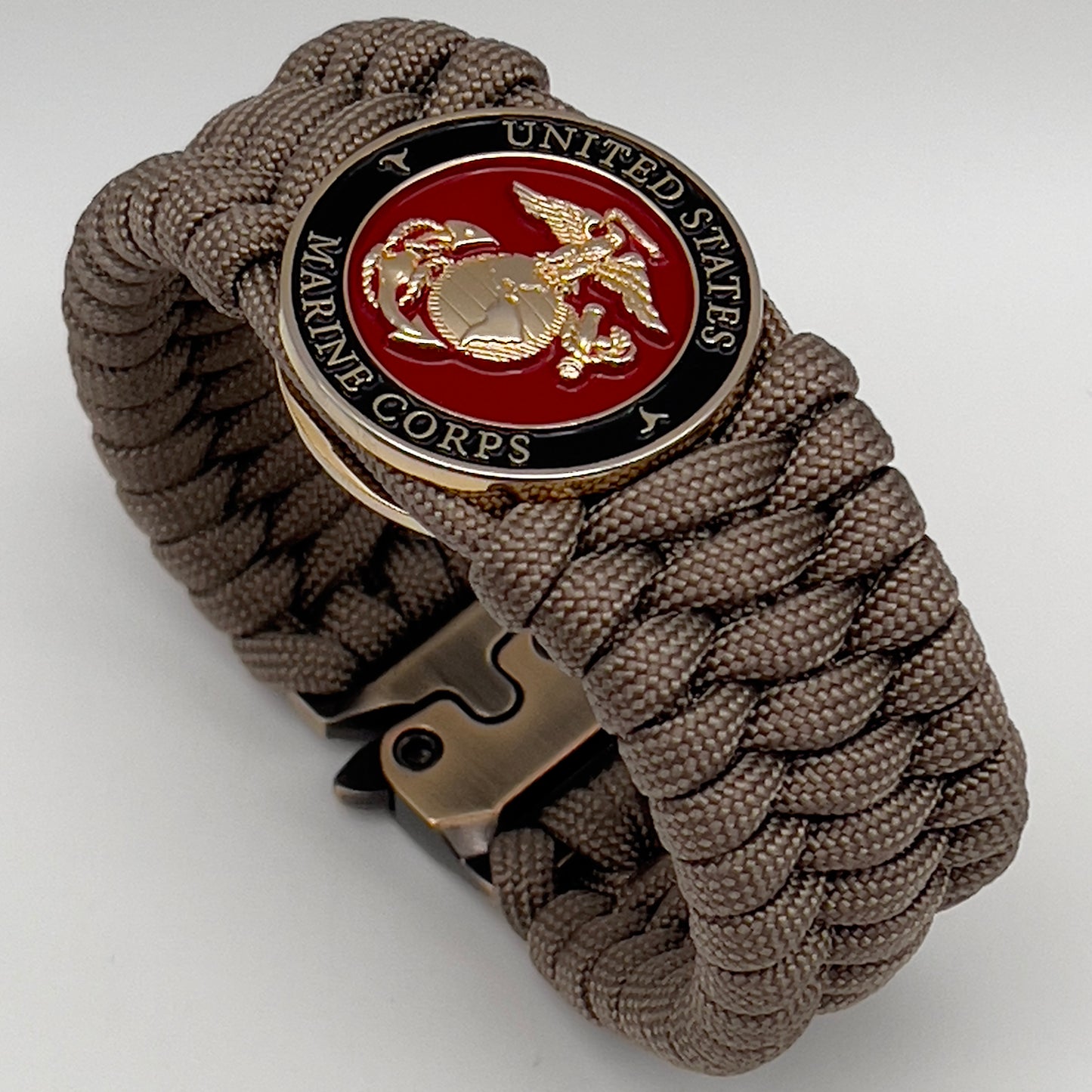 Thick, wide, semi-rigid and comfortable braided United States Marine Corps bracelet featuring a 24K gold plated USMC Eagle Globe and Anchor medallion, a gold Cobra style tactical buckle and woven with tan 550 paracord.