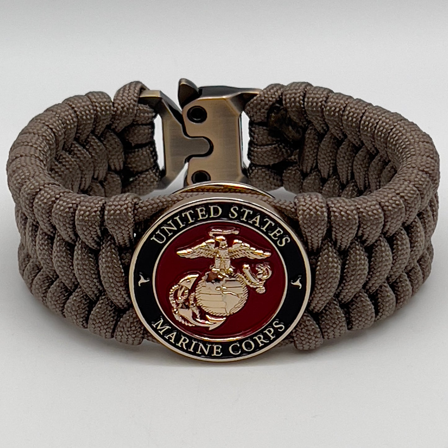 Thick, wide, semi-rigid and comfortable braided United States Marine Corps bracelet featuring a 24K gold plated USMC Eagle Globe and Anchor medallion, a gold Cobra style tactical buckle and woven with tan 550 paracord.