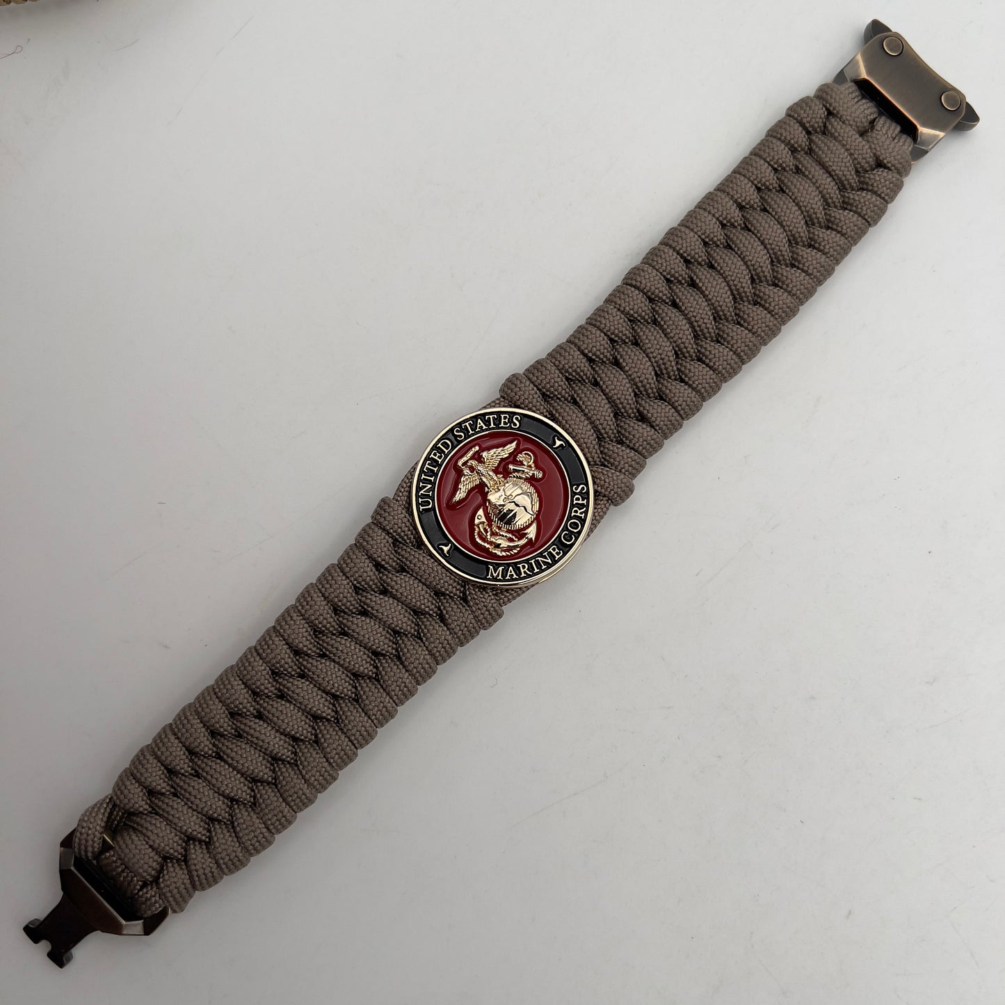 Thick, wide, semi-rigid and comfortable braided United States Marine Corps bracelet featuring a 24K gold plated USMC Eagle Globe and Anchor medallion, a gold Cobra style tactical buckle and woven with tan 550 paracord.