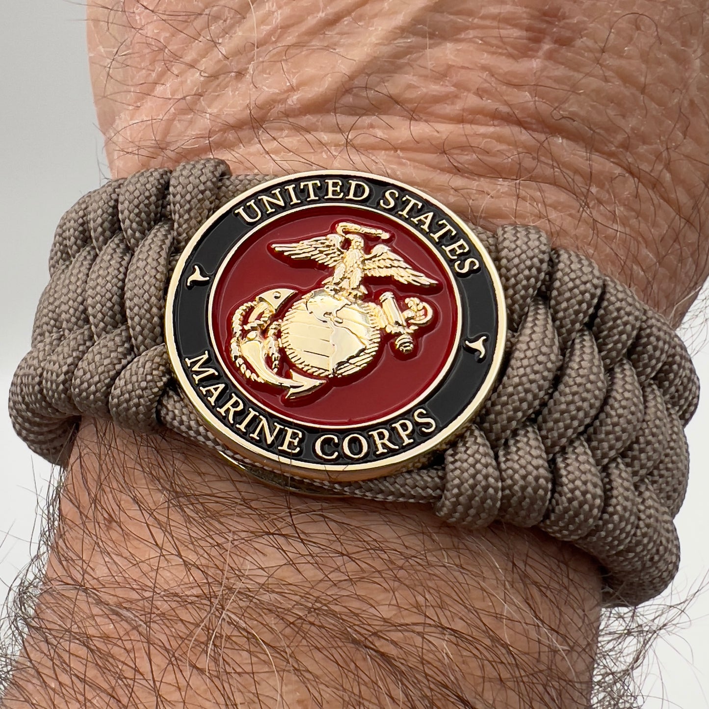Thick, wide, semi-rigid and comfortable braided United States Marine Corps bracelet featuring a 24K gold plated USMC Eagle Globe and Anchor medallion, a gold Cobra style tactical buckle and woven with tan 550 paracord.