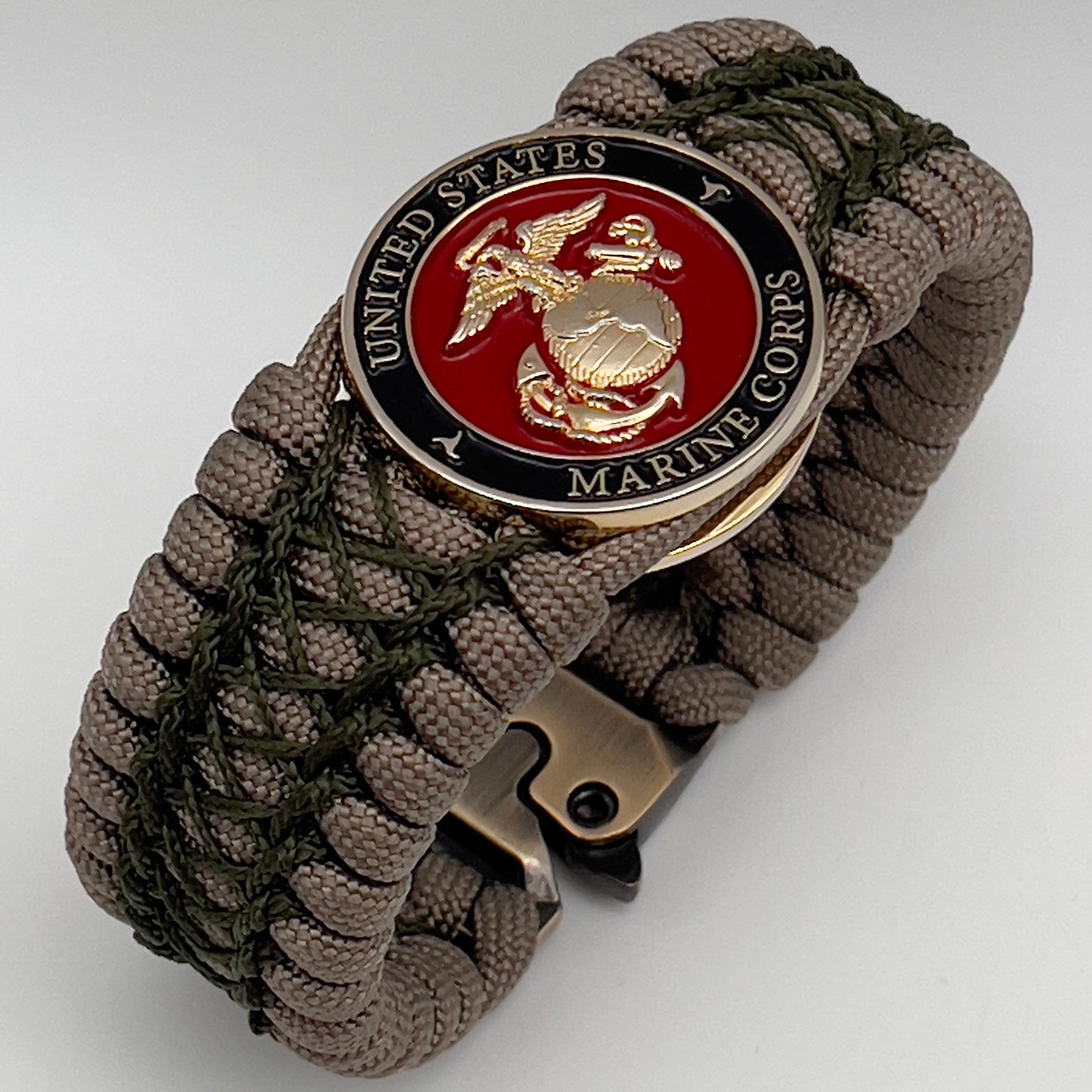 Thick, wide, rigid and comfortable braided United States Marine Corps bracelet featuring a 24K gold plated USMC Eagle Globe and Anchor medallion, a gold Cobra style tactical buckle and woven with tan 550 paracord and olive drab nano and micro cord.