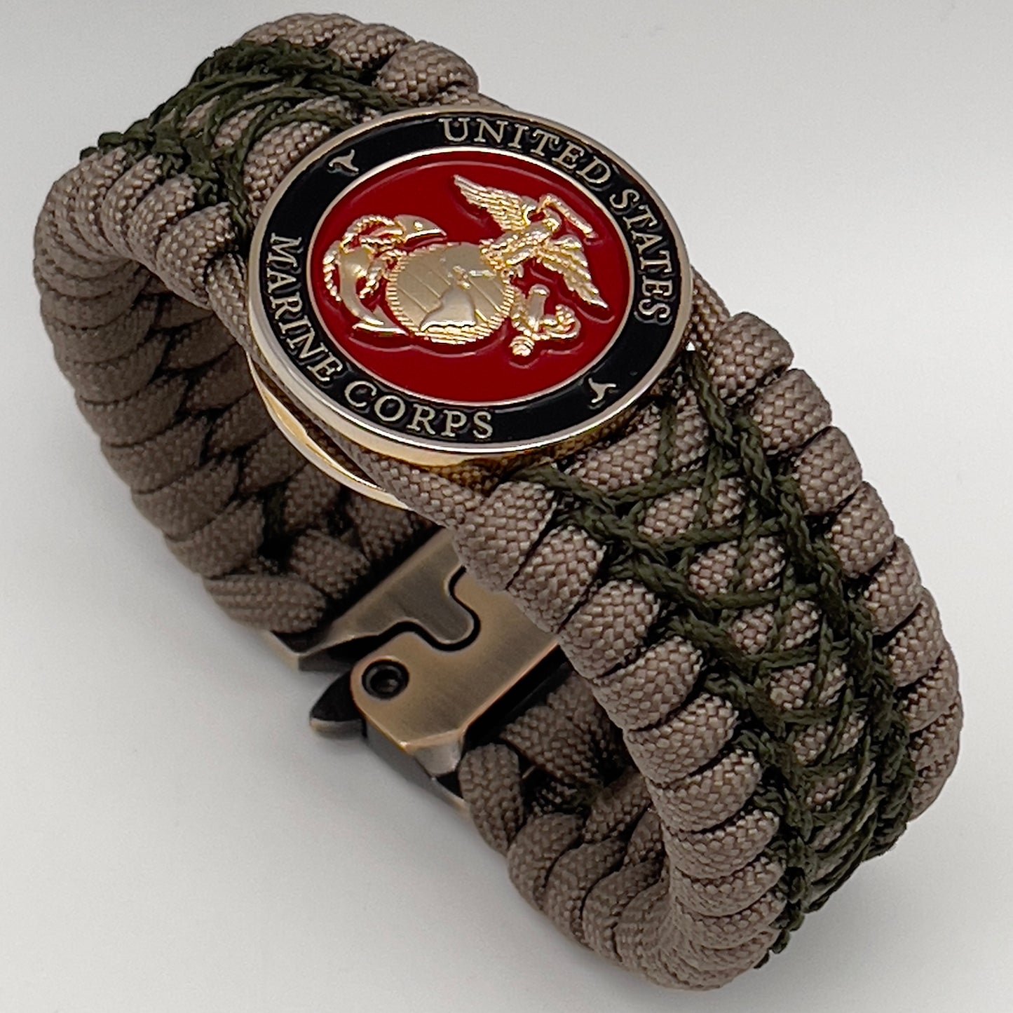 Thick, wide, rigid and comfortable braided United States Marine Corps bracelet featuring a 24K gold plated USMC Eagle Globe and Anchor medallion, a gold Cobra style tactical buckle and woven with tan 550 paracord and olive drab nano and micro cord.