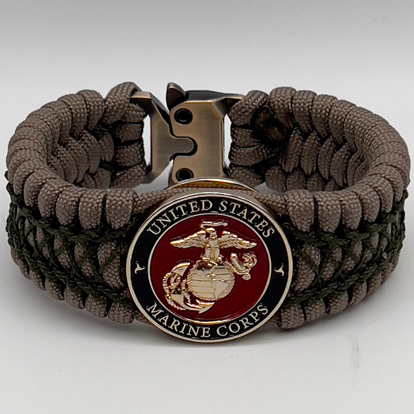 Thick, wide, rigid and comfortable braided United States Marine Corps bracelet featuring a 24K gold plated USMC Eagle Globe and Anchor medallion, a gold Cobra style tactical buckle and woven with tan 550 paracord and olive drab nano and micro cord.