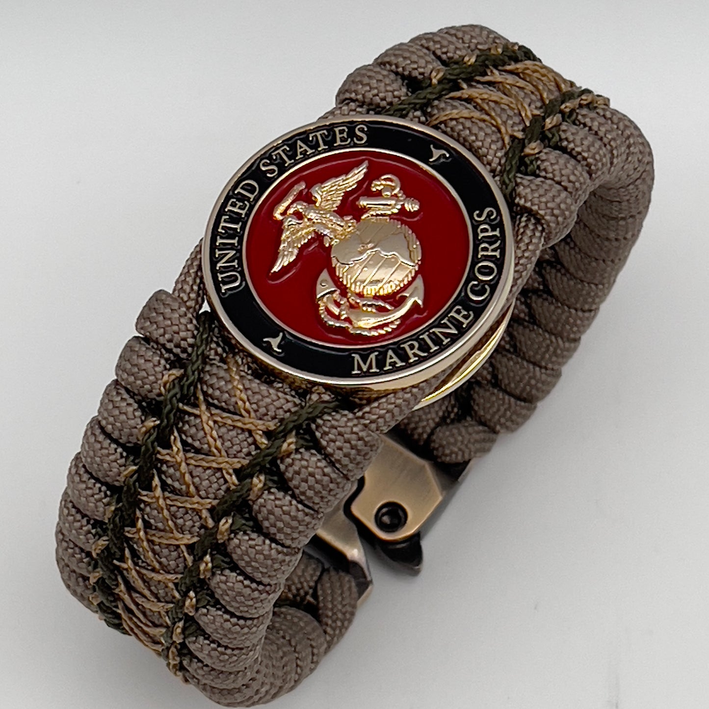 Thick, wide, rigid and comfortable braided United States Marine Corps bracelet featuring a 24K gold plated USMC Eagle Globe and Anchor medallion, a gold Cobra style tactical buckle and woven with tan 550 paracord and olive drab micro and tan nano cord.