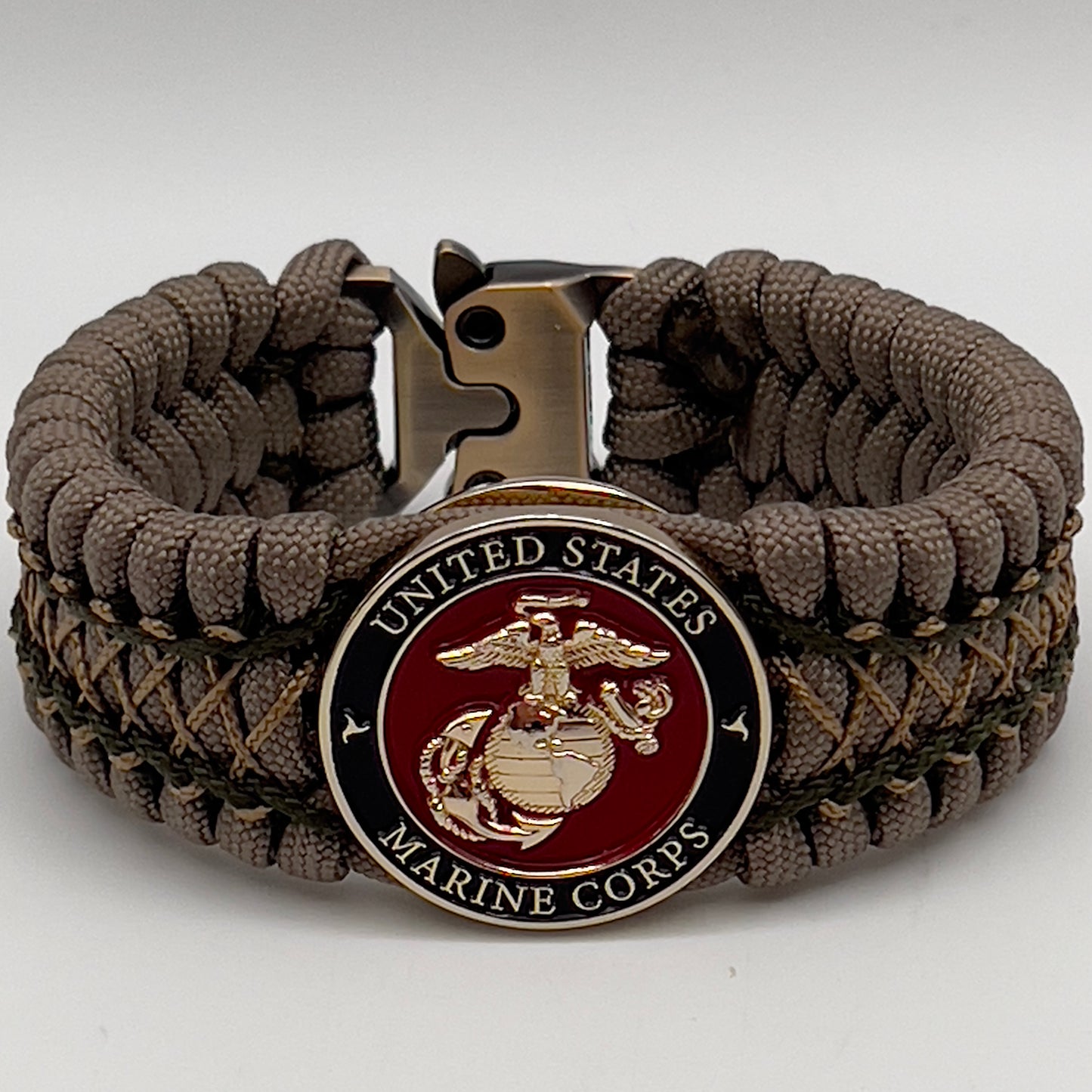 Thick, wide, rigid and comfortable braided United States Marine Corps bracelet featuring a 24K gold plated USMC Eagle Globe and Anchor medallion, a gold Cobra style tactical buckle and woven with tan 550 paracord and olive drab micro and tan nano cord.
