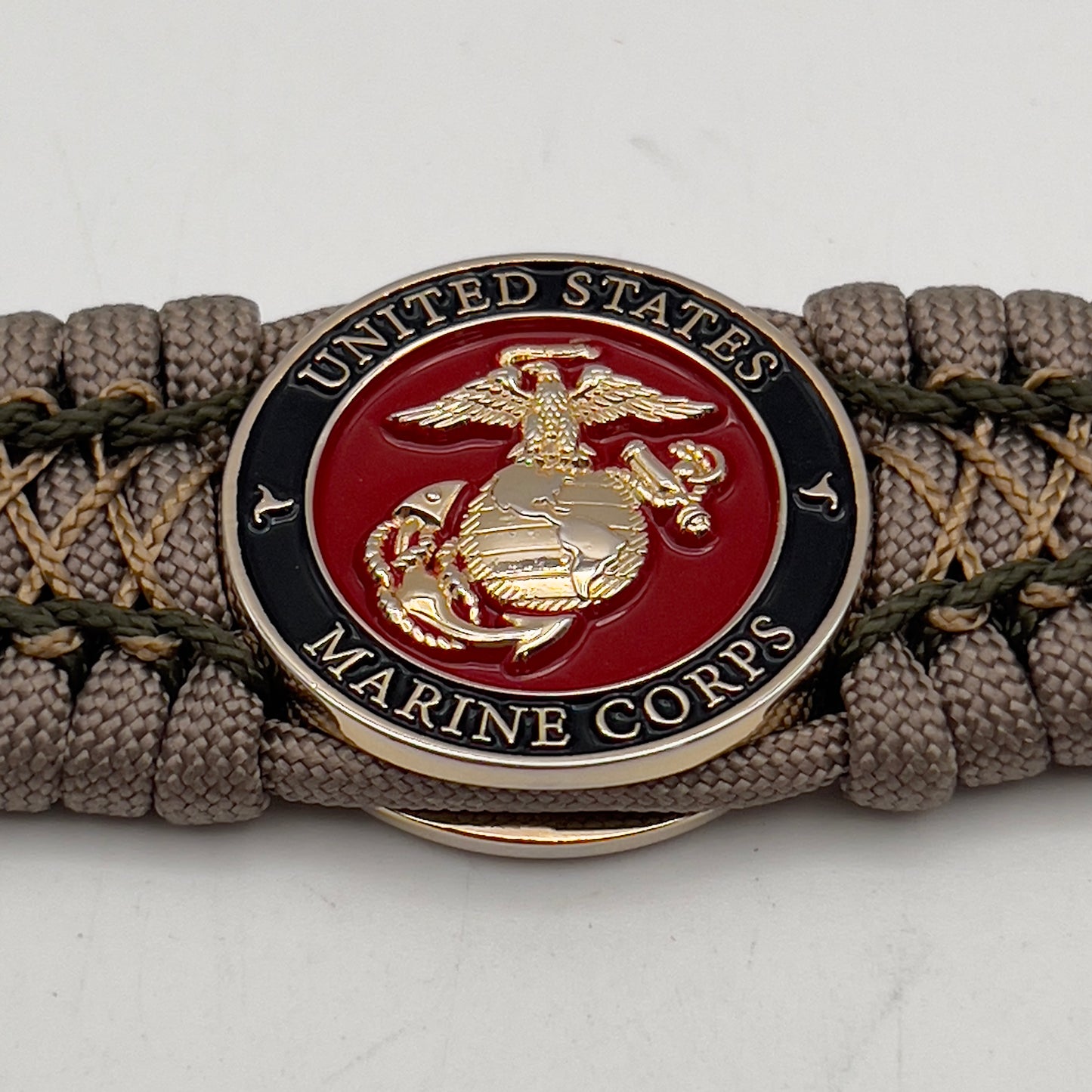 Thick, wide, rigid and comfortable braided United States Marine Corps bracelet featuring a 24K gold plated USMC Eagle Globe and Anchor medallion, a gold Cobra style tactical buckle and woven with tan 550 paracord and olive drab micro and tan nano cord.