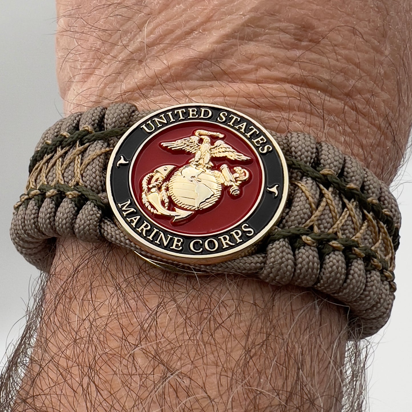 Thick, wide, rigid and comfortable braided United States Marine Corps bracelet featuring a 24K gold plated USMC Eagle Globe and Anchor medallion, a gold Cobra style tactical buckle and woven with tan 550 paracord and olive drab micro and tan nano cord.