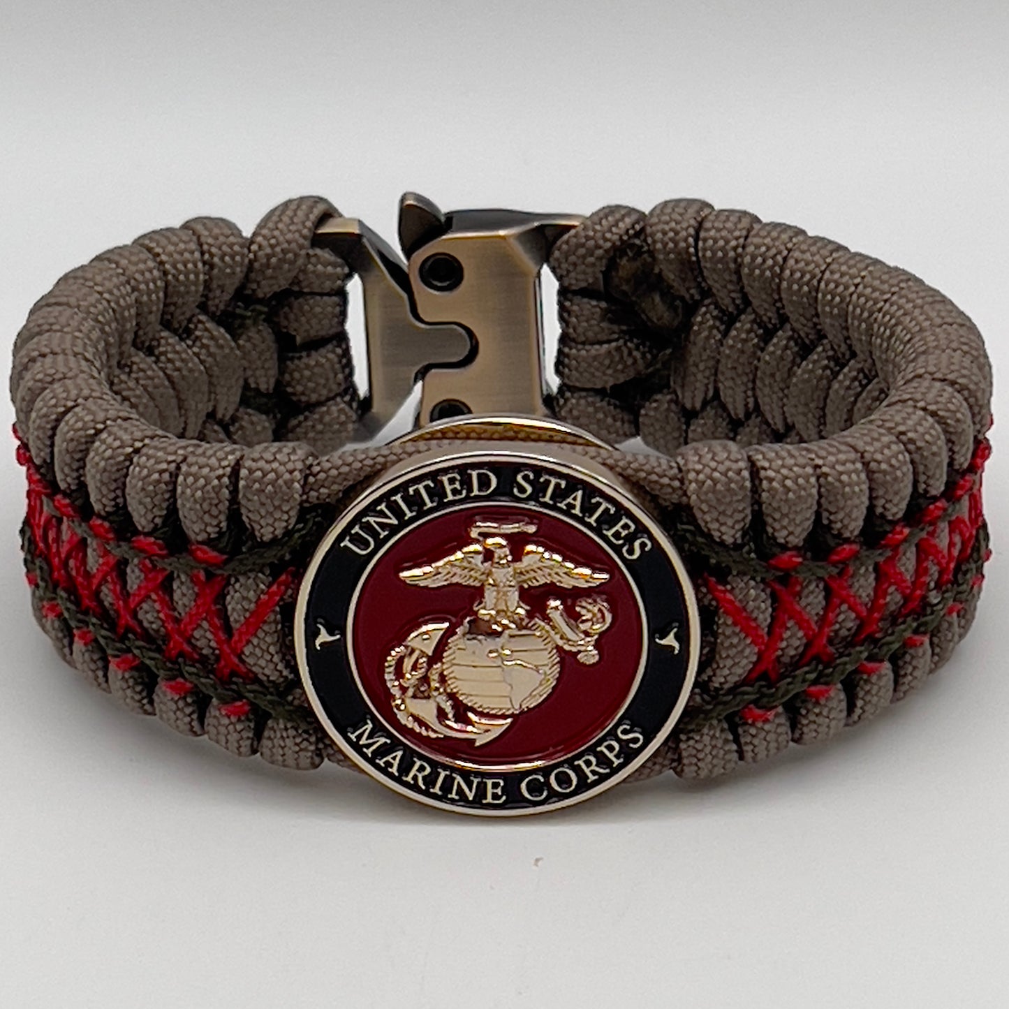 Thick, wide, rigid and comfortable braided United States Marine Corps bracelet featuring a 24K gold plated USMC Eagle Globe and Anchor medallion, a gold Cobra style tactical buckle and woven with tan 550 paracord, olive drab micro and Imperial red nano cord.