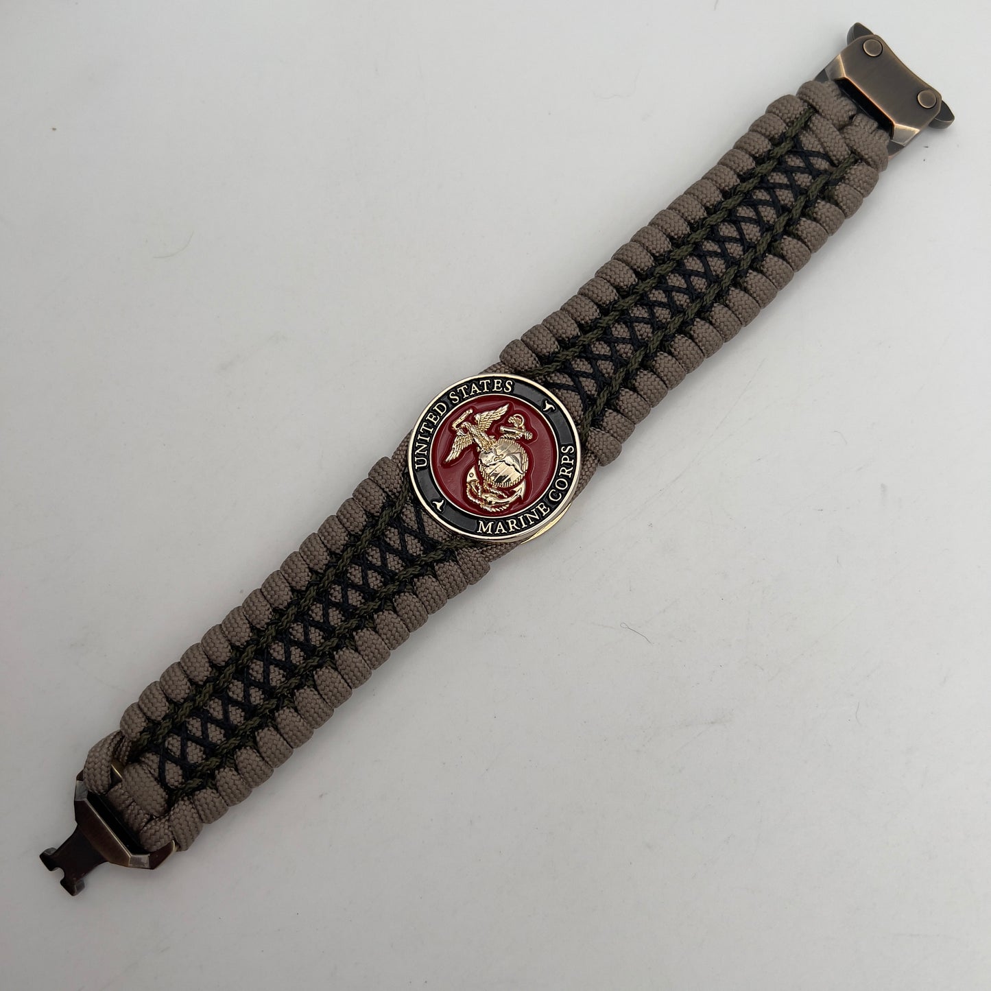 Thick, wide, rigid and comfortable braided United States Marine Corps bracelet featuring a 24K gold plated USMC Eagle Globe and Anchor medallion, a gold Cobra style tactical buckle and woven with tan 550 paracord, olive drab micro and black nano cord.