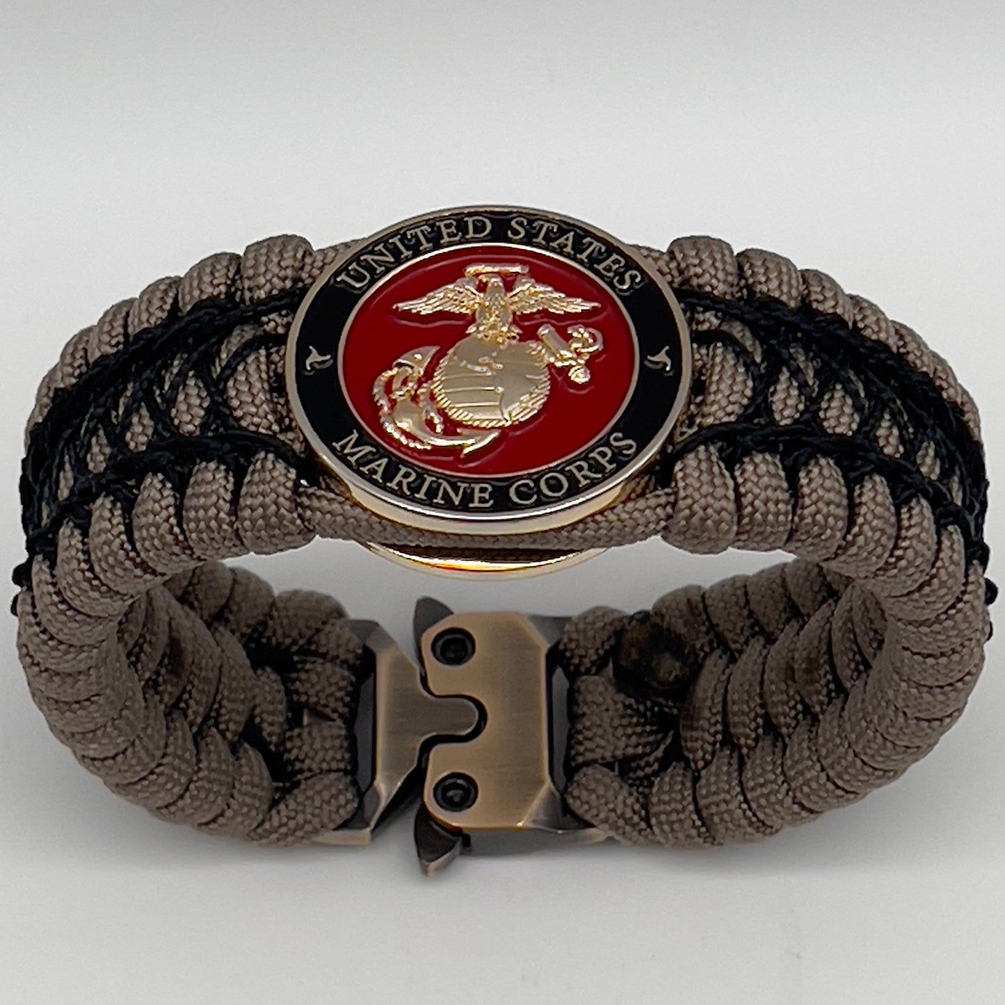 Thick, wide, rigid and comfortable braided United States Marine Corps bracelet featuring a 24K gold plated USMC Eagle Globe and Anchor medallion, a gold Cobra style tactical buckle and woven with tan 550 paracord and black nano and micro cord.