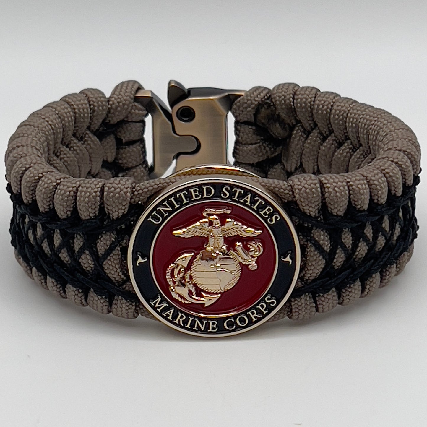 Thick, wide, rigid and comfortable braided United States Marine Corps bracelet featuring a 24K gold plated USMC Eagle Globe and Anchor medallion, a gold Cobra style tactical buckle and woven with tan 550 paracord and black nano and micro cord.