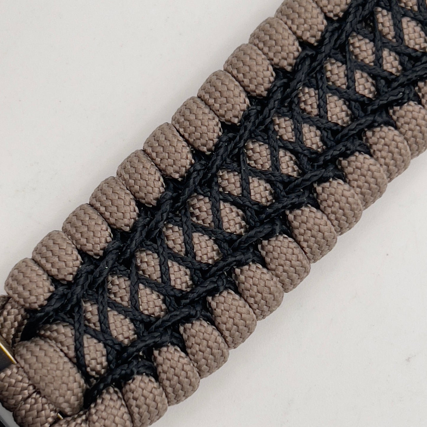 Thick, wide, rigid and comfortable braided United States Marine Corps bracelet featuring a 24K gold plated USMC Eagle Globe and Anchor medallion, a gold Cobra style tactical buckle and woven with tan 550 paracord and black nano and micro cord.