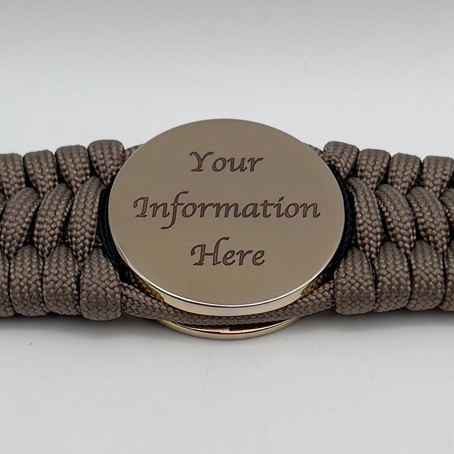 Thick, wide, rigid and comfortable braided United States Marine Corps bracelet featuring a 24K gold plated USMC Eagle Globe and Anchor medallion, a gold Cobra style tactical buckle and woven with tan 550 paracord and black nano and micro cord.