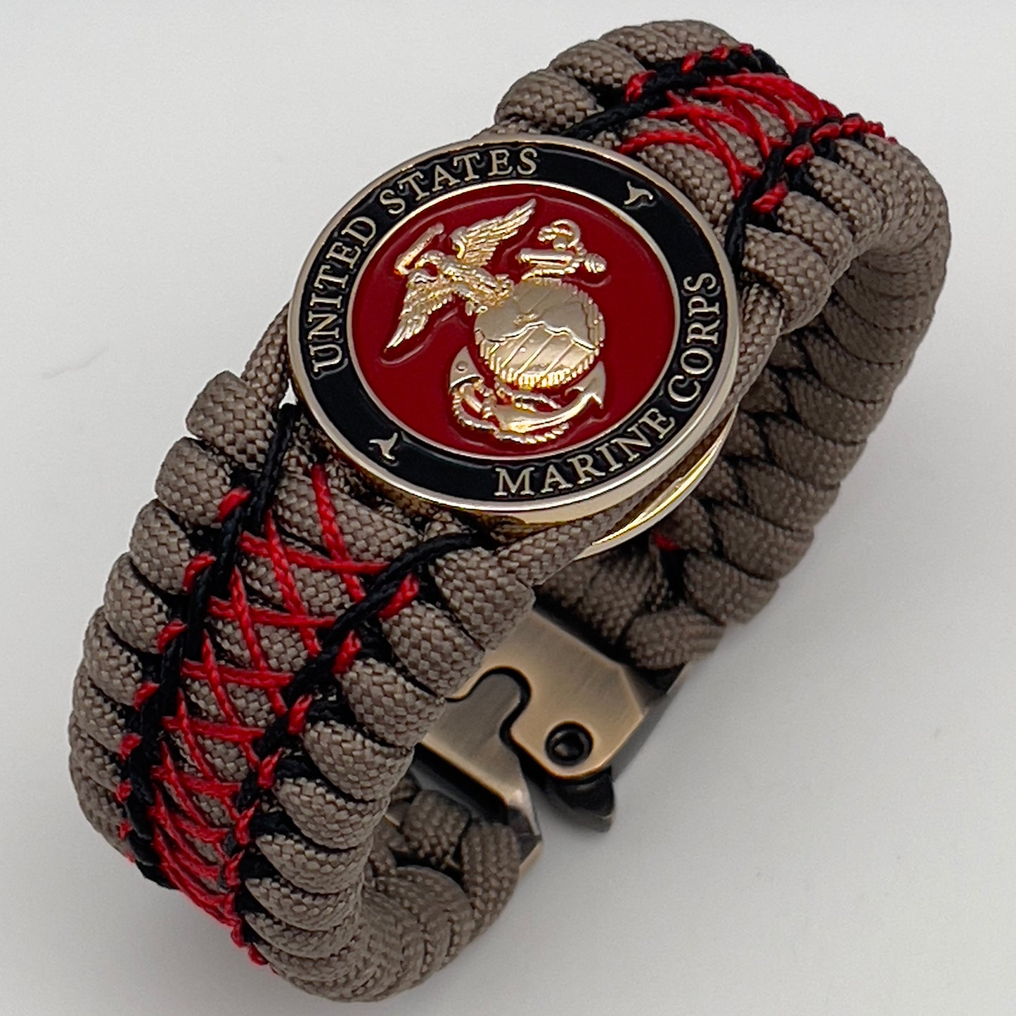Thick, wide, rigid and comfortable handwoven United States Marine Corps bracelet featuring a 24K gold plated USMC Eagle Globe and Anchor medallion, a gold Cobra style tactical buckle and woven with tna 550 paracord, black micro cord and red nano cord.