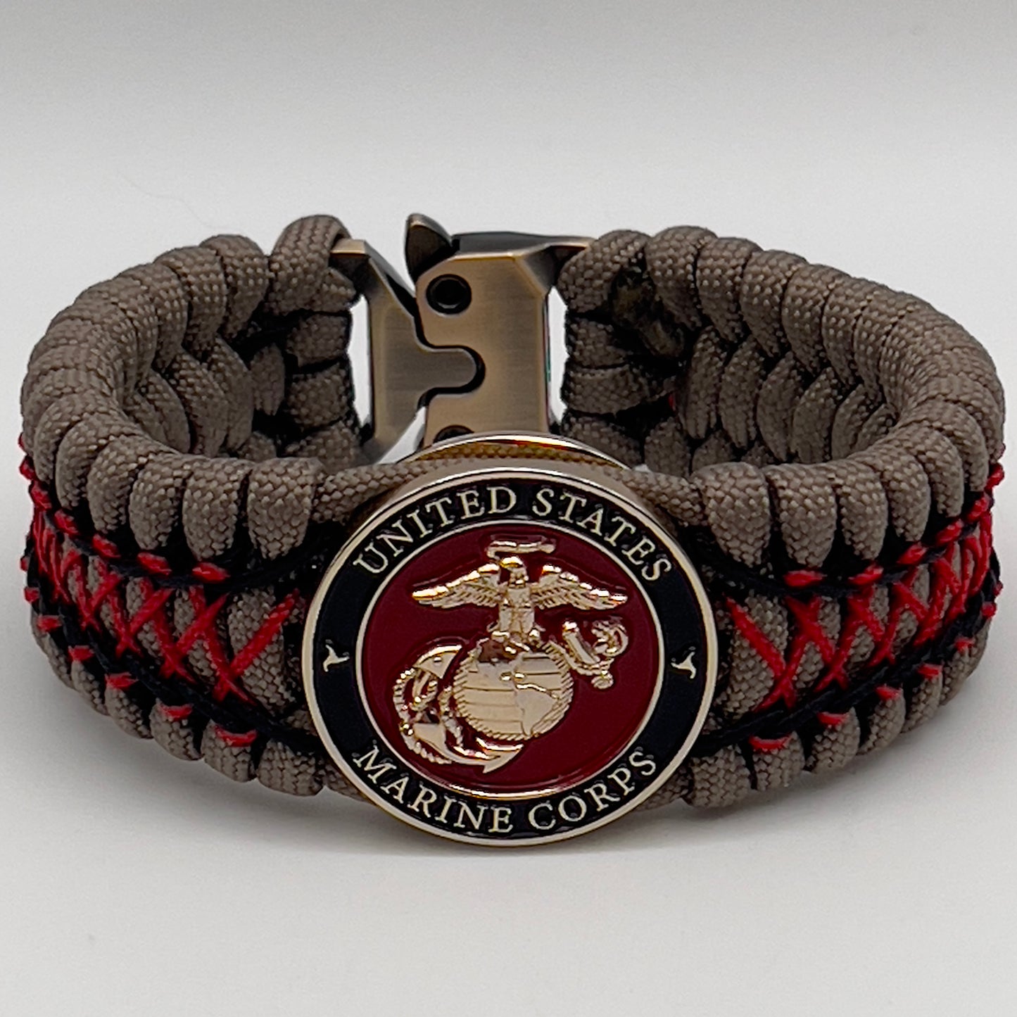 Thick, wide, rigid and comfortable handwoven United States Marine Corps bracelet featuring a 24K gold plated USMC Eagle Globe and Anchor medallion, a gold Cobra style tactical buckle and woven with tna 550 paracord, black micro cord and red nano cord.
