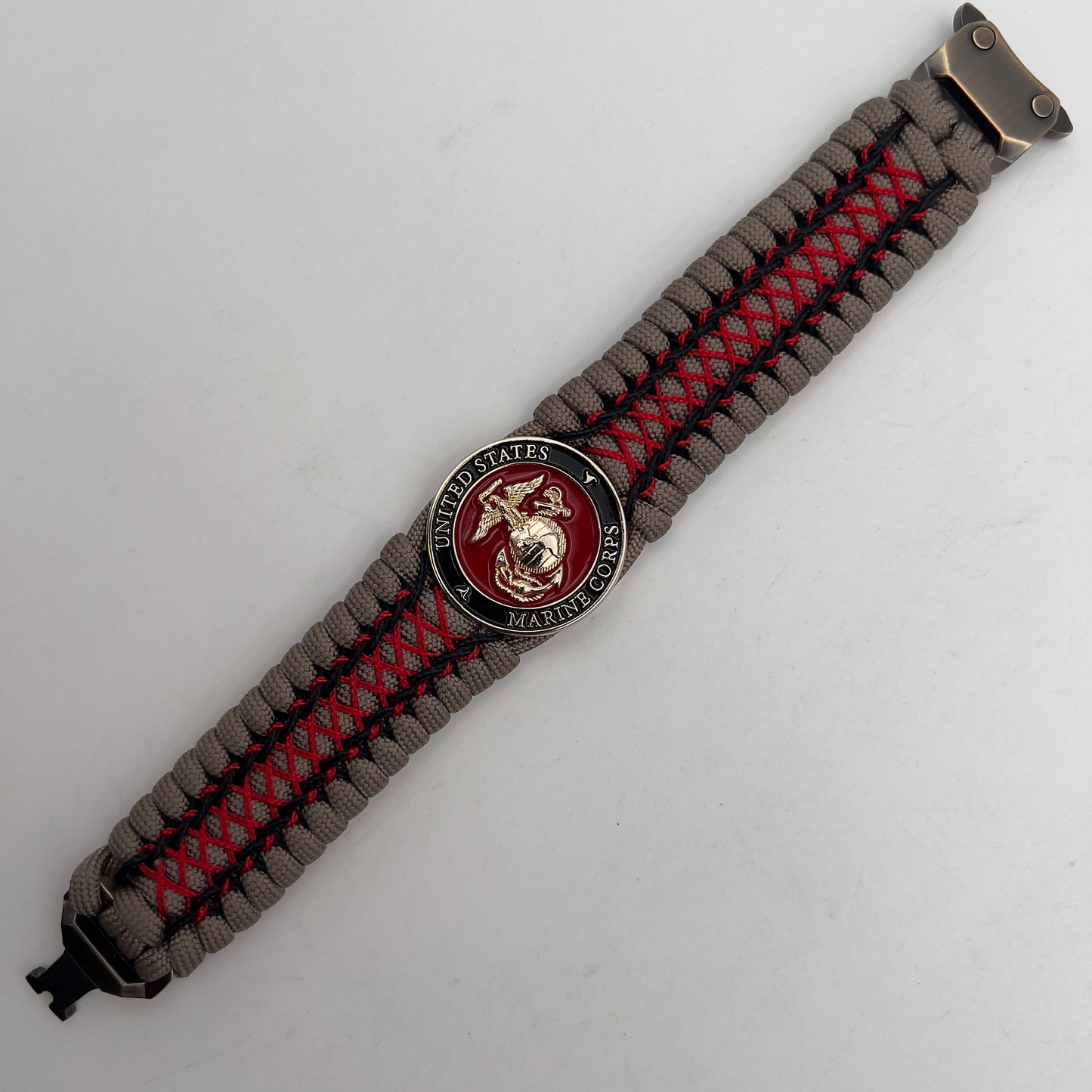 Thick, wide, rigid and comfortable handwoven United States Marine Corps bracelet featuring a 24K gold plated USMC Eagle Globe and Anchor medallion, a gold Cobra style tactical buckle and woven with tna 550 paracord, black micro cord and red nano cord.