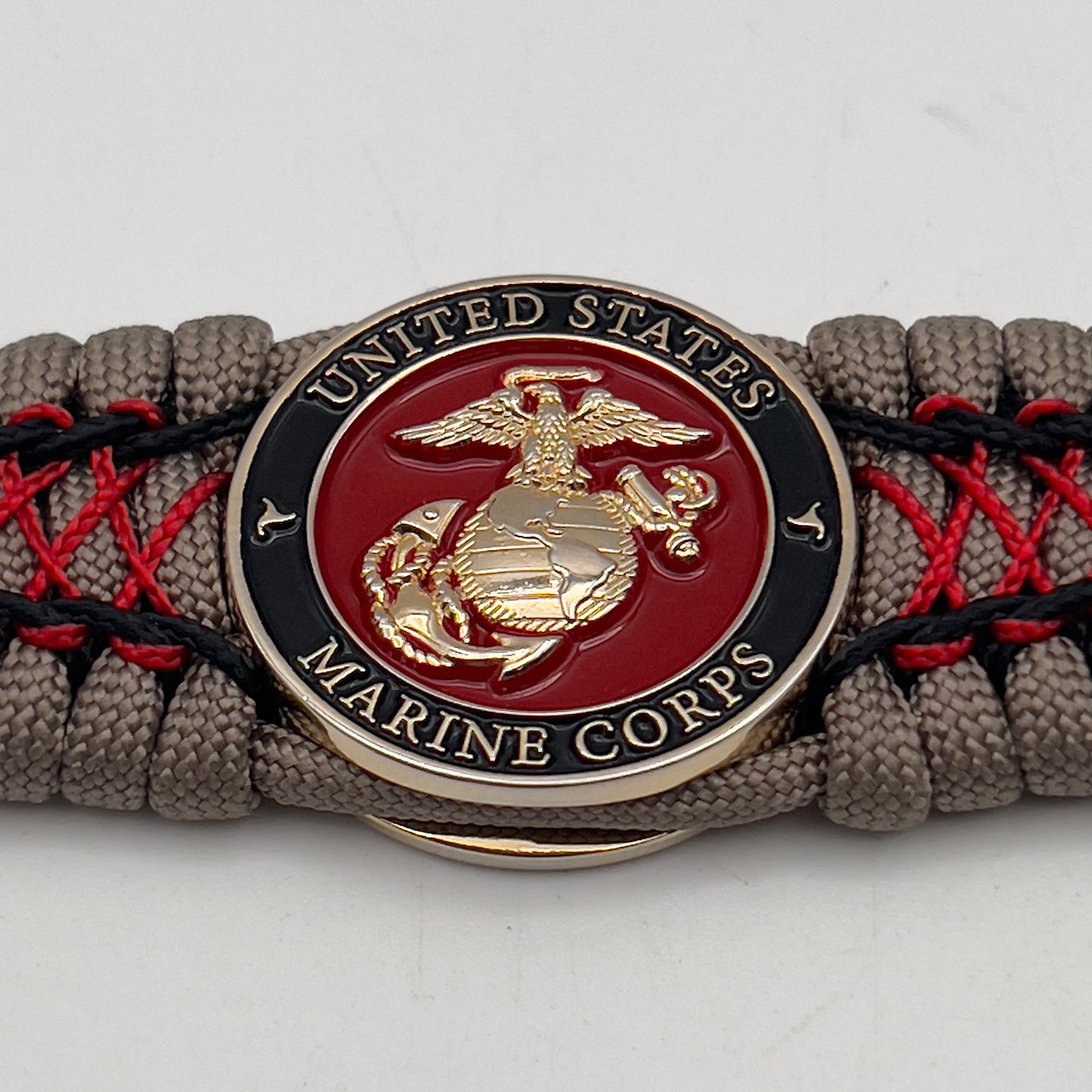 Thick, wide, rigid and comfortable handwoven United States Marine Corps bracelet featuring a 24K gold plated USMC Eagle Globe and Anchor medallion, a gold Cobra style tactical buckle and woven with tna 550 paracord, black micro cord and red nano cord.