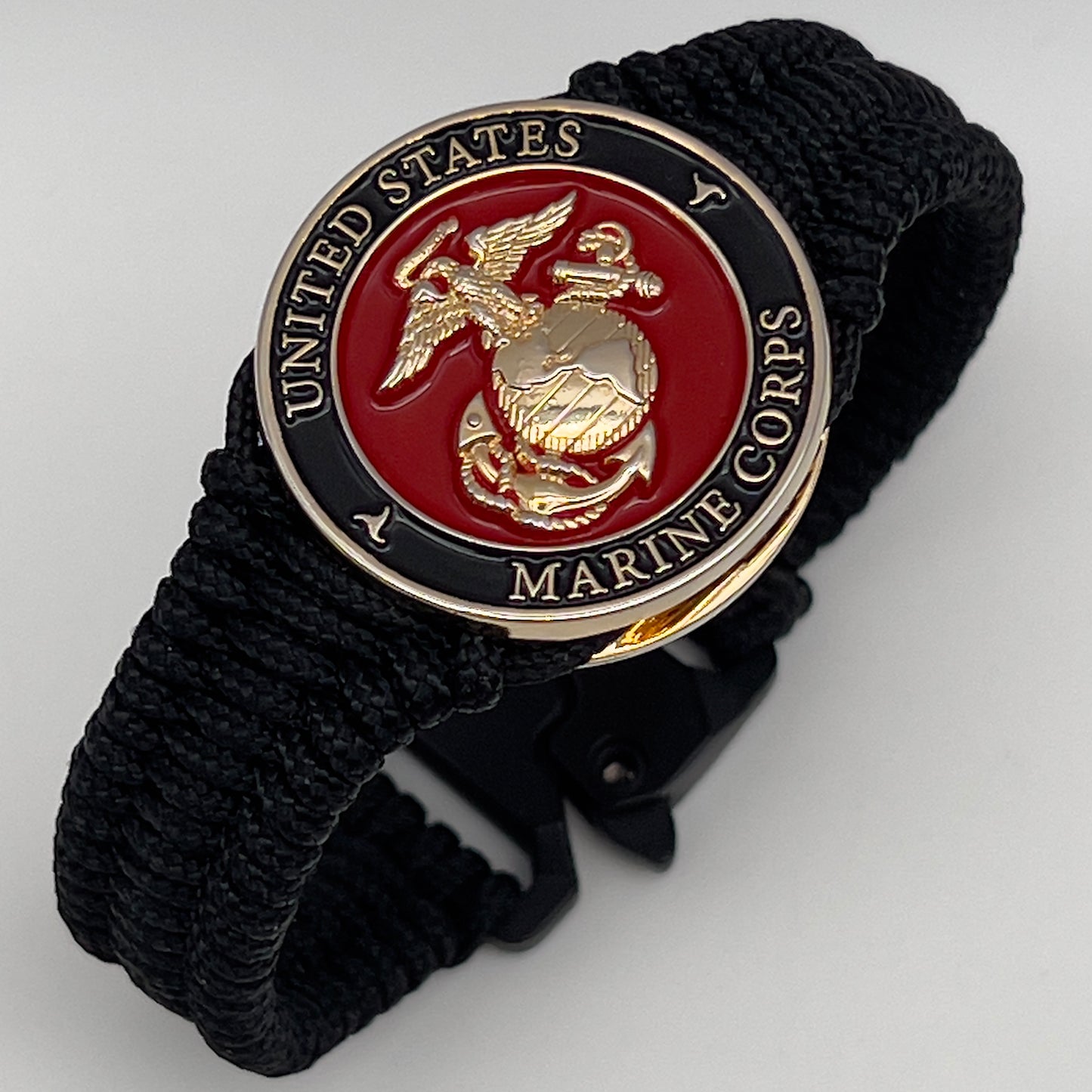 Thick, narrow, flexible and comfortable braided United States Marine Corps bracelet featuring a 24K gold plated USMC officer Eagle Globe and Anchor medallion, a black Cobra style tactical buckle and woven with black Type-1 paracord.