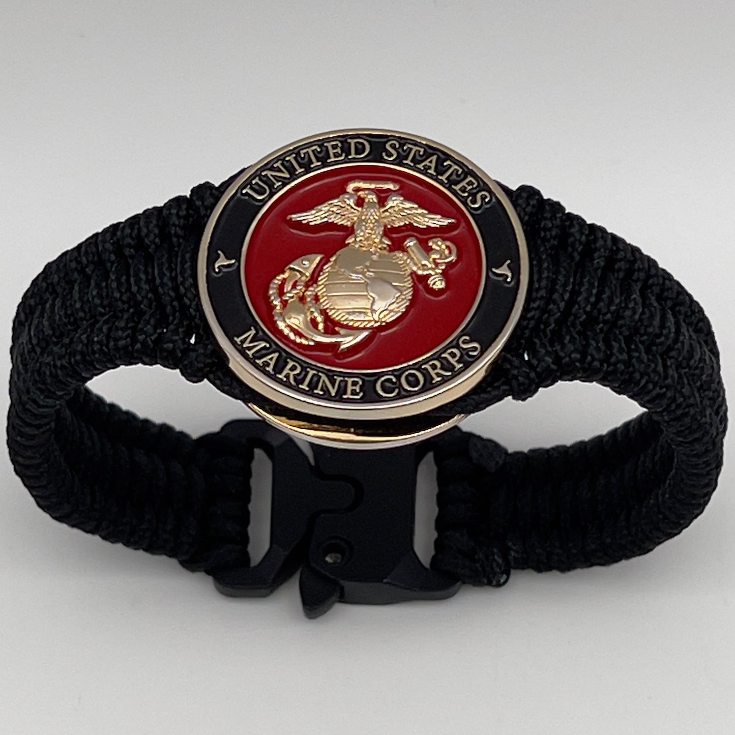 Thick, narrow, flexible and comfortable braided United States Marine Corps bracelet featuring a 24K gold plated USMC officer Eagle Globe and Anchor medallion, a black Cobra style tactical buckle and woven with black Type-1 paracord.