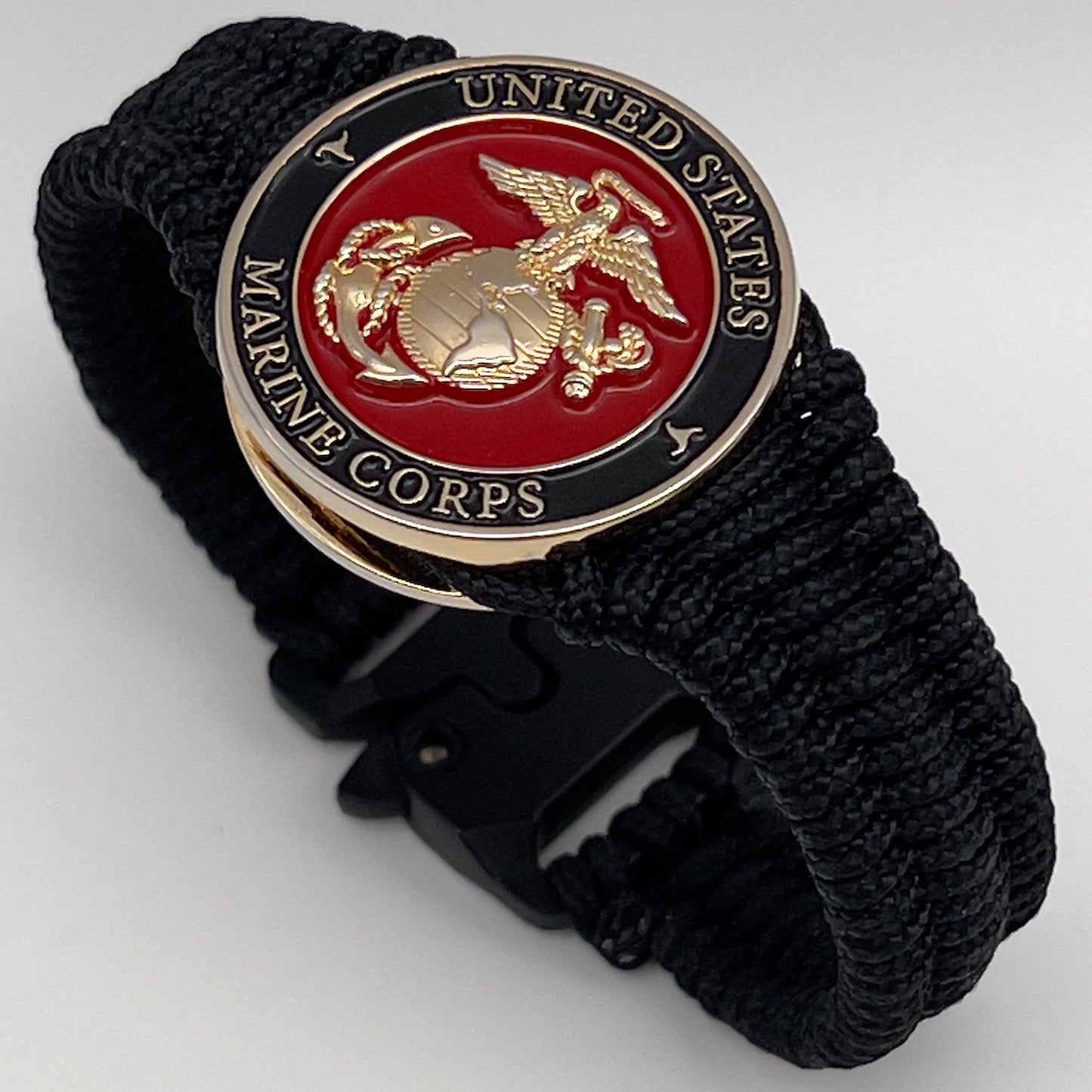 Thick, narrow, flexible and comfortable braided United States Marine Corps bracelet featuring a 24K gold plated USMC officer Eagle Globe and Anchor medallion, a black Cobra style tactical buckle and woven with black Type-1 paracord.