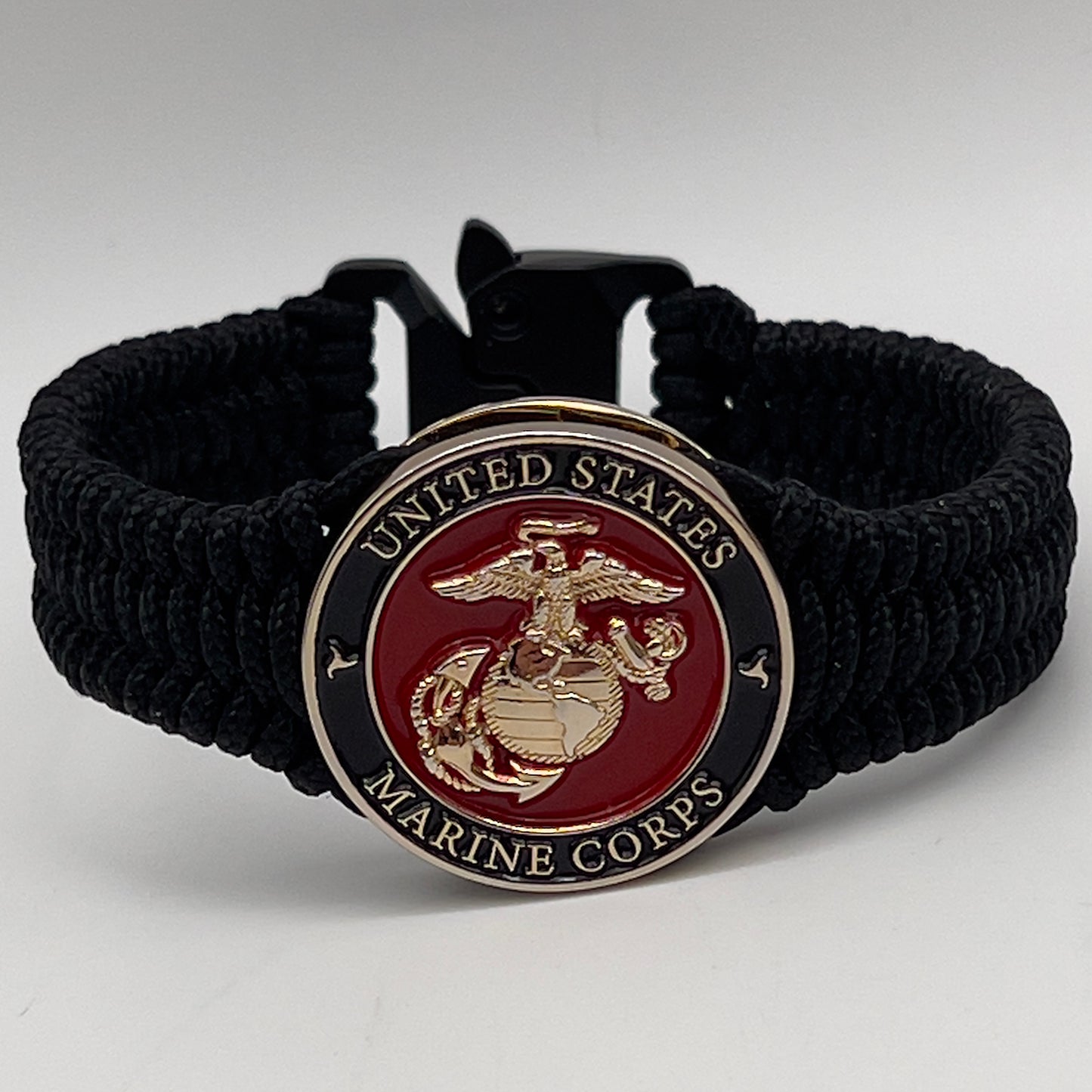 Thick, narrow, flexible and comfortable braided United States Marine Corps bracelet featuring a 24K gold plated USMC officer Eagle Globe and Anchor medallion, a black Cobra style tactical buckle and woven with black Type-1 paracord.