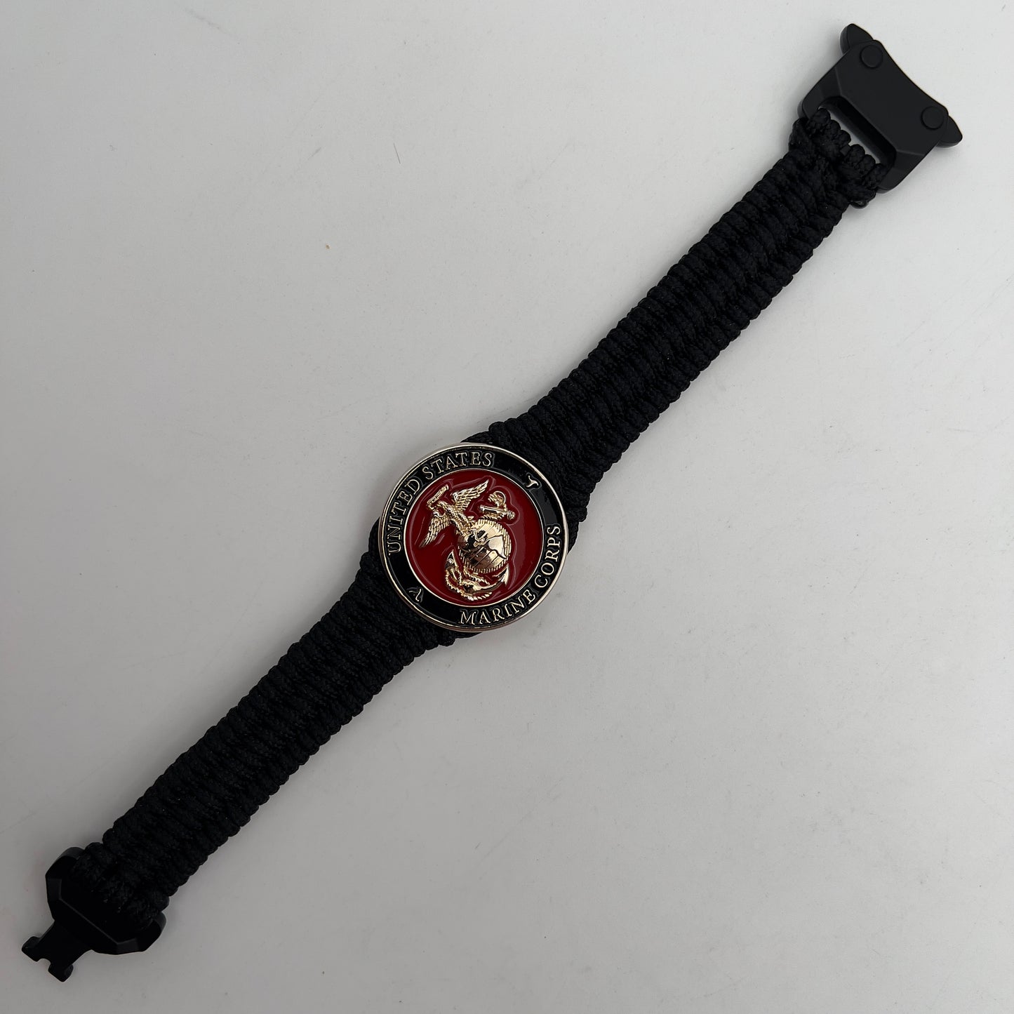Thick, narrow, flexible and comfortable braided United States Marine Corps bracelet featuring a 24K gold plated USMC officer Eagle Globe and Anchor medallion, a black Cobra style tactical buckle and woven with black Type-1 paracord.