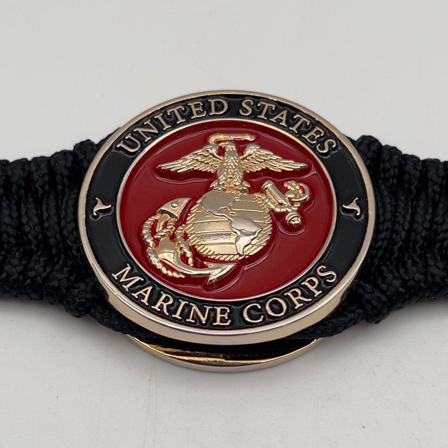 Thick, narrow, flexible and comfortable braided United States Marine Corps bracelet featuring a 24K gold plated USMC officer Eagle Globe and Anchor medallion, a black Cobra style tactical buckle and woven with black Type-1 paracord.