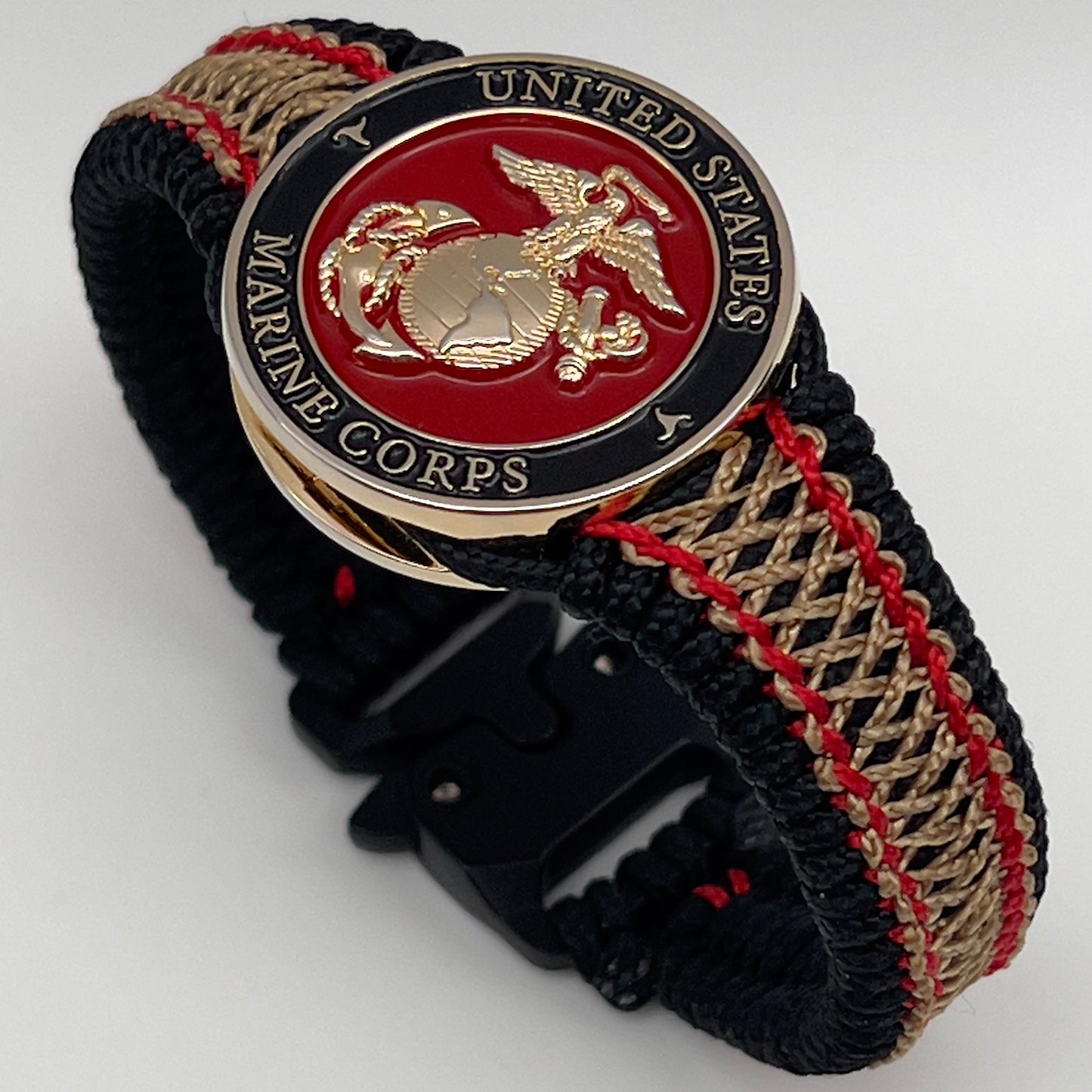 Thin, narrow, flexible and comfortable braided United States Marine Corps bracelet featuring a 24K gold plated USMC Eagle Globe and Anchor medallion, a black Cobra style tactical buckle and woven with black Type-1 paracord and Imperial Red and Gold nano cord.