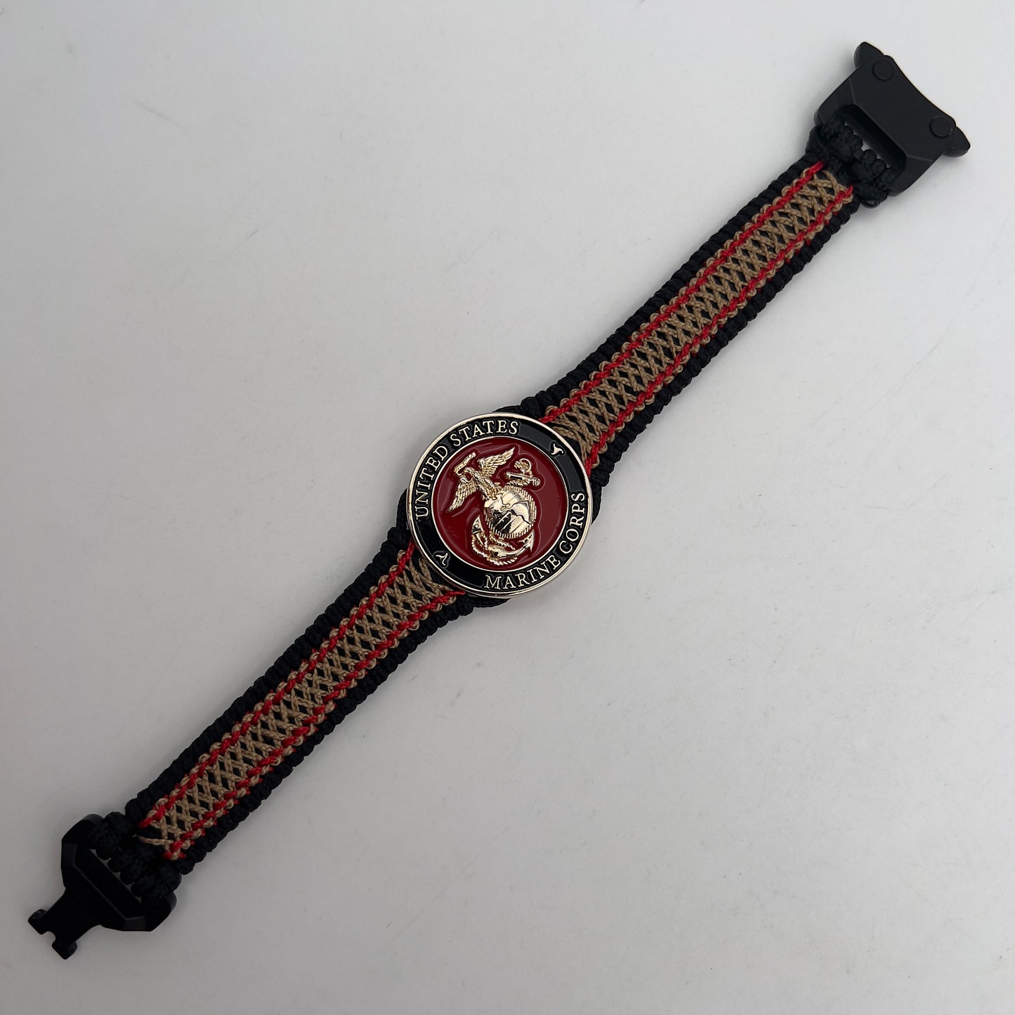 Thin, narrow, flexible and comfortable braided United States Marine Corps bracelet featuring a 24K gold plated USMC Eagle Globe and Anchor medallion, a black Cobra style tactical buckle and woven with black Type-1 paracord and Imperial Red and Gold nano cord.